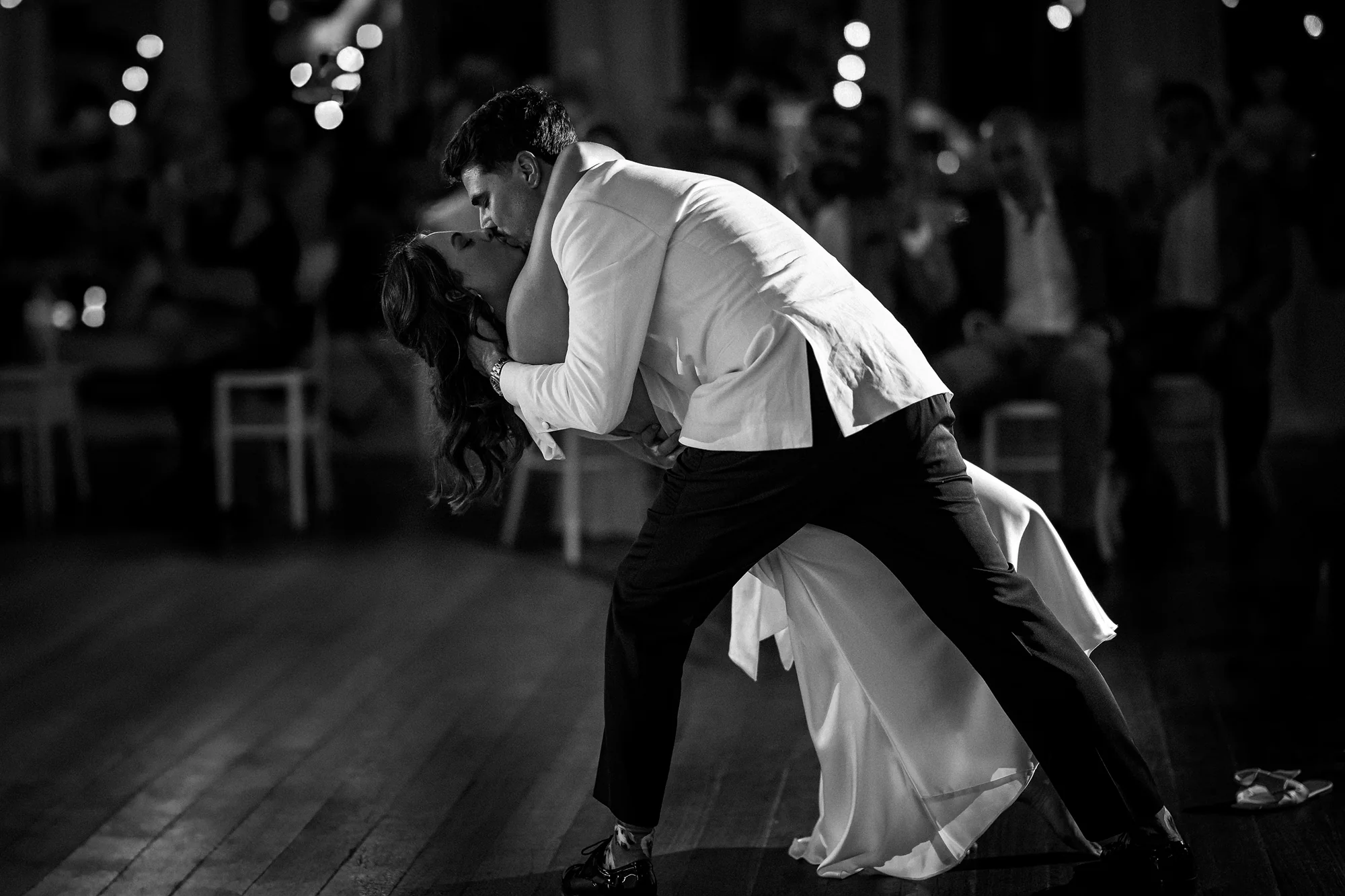 In black and white, the groom dips the bride into a kiss on an empty dance floor.