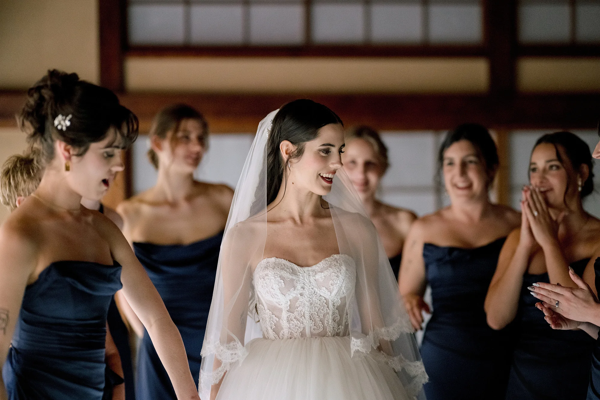 Bridesmaids gasp and laugh as they see the bride for the first time.