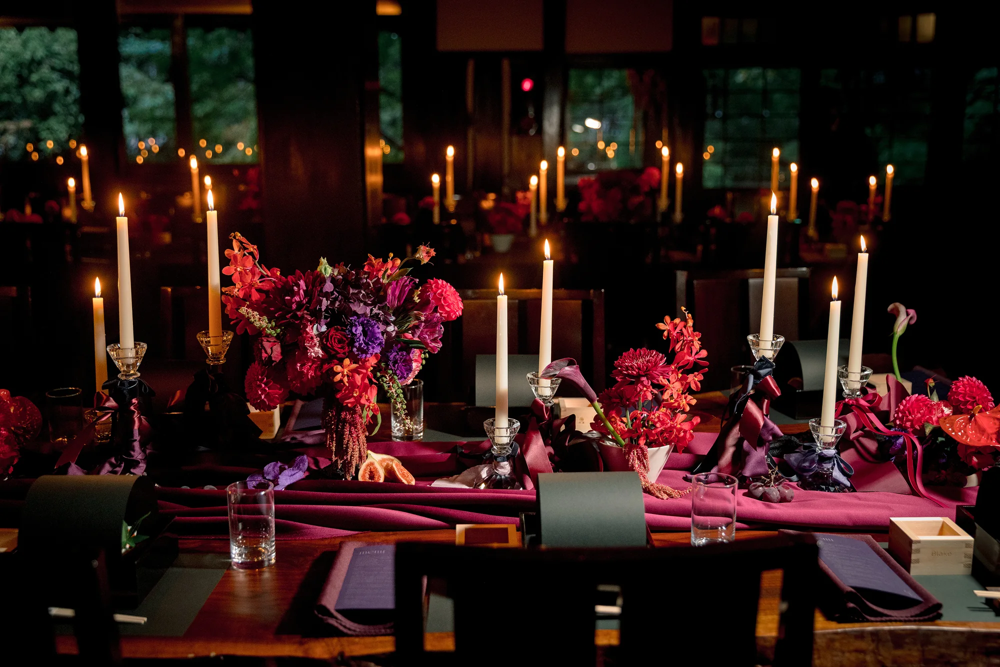 Tall candles, deep red flowers and figs crowd the reception table at a Gothic-inspired wedding at Jinya.