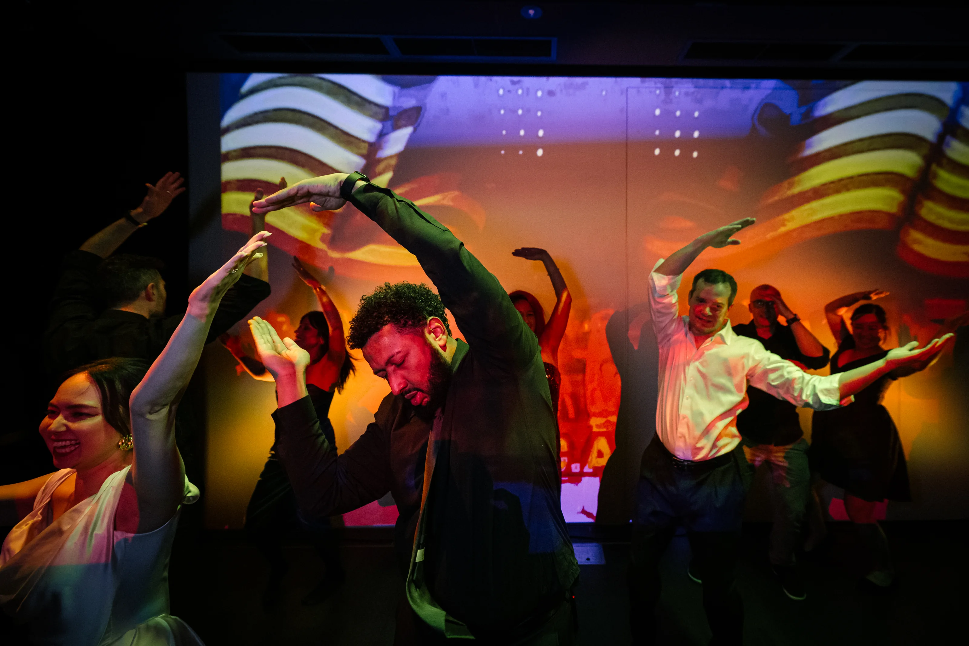 Guests dance under colored light at a late-night wedding party.