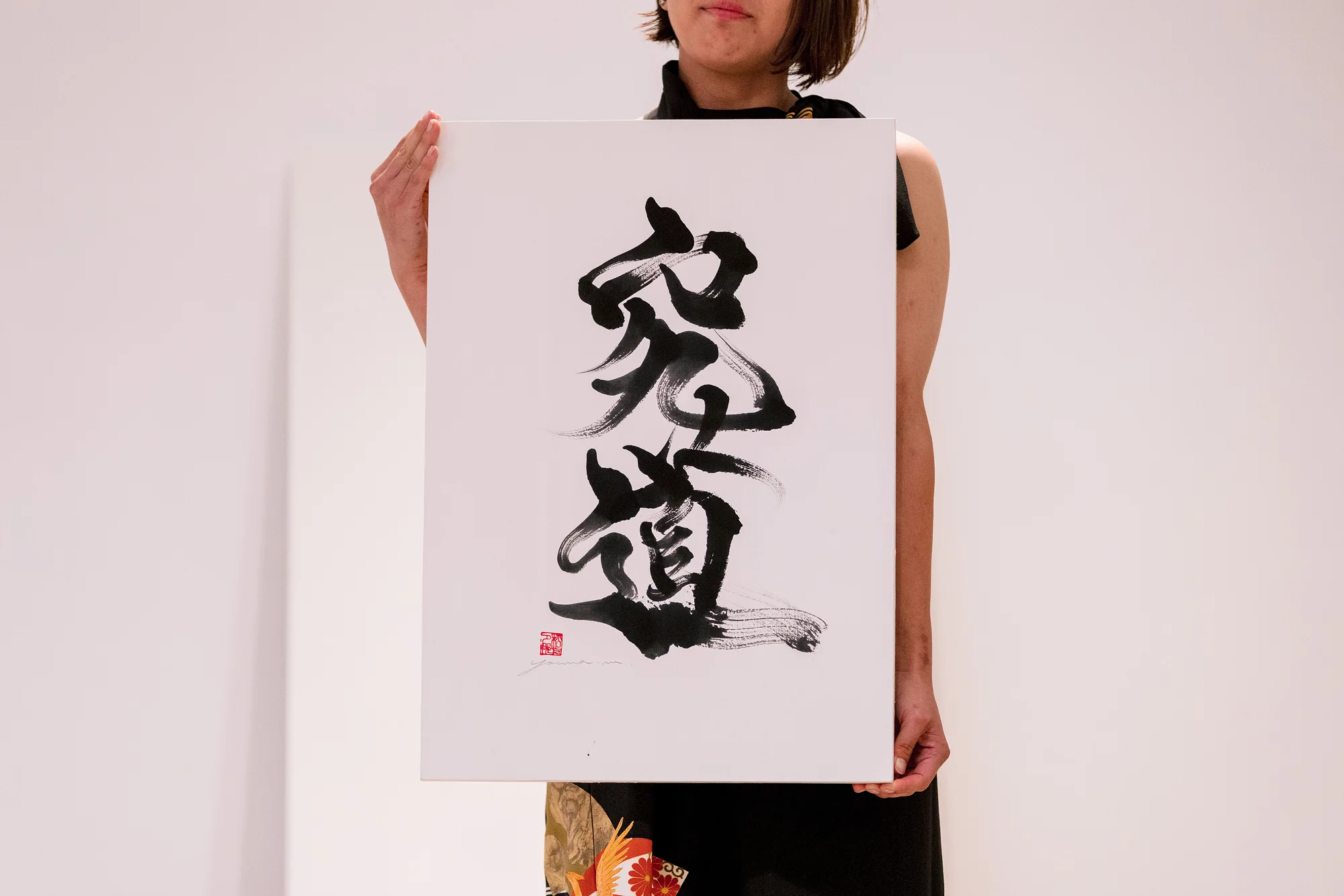 The finished calligraphy, two bold characters in black ink, held up for the guests at a wedding in Hakone.