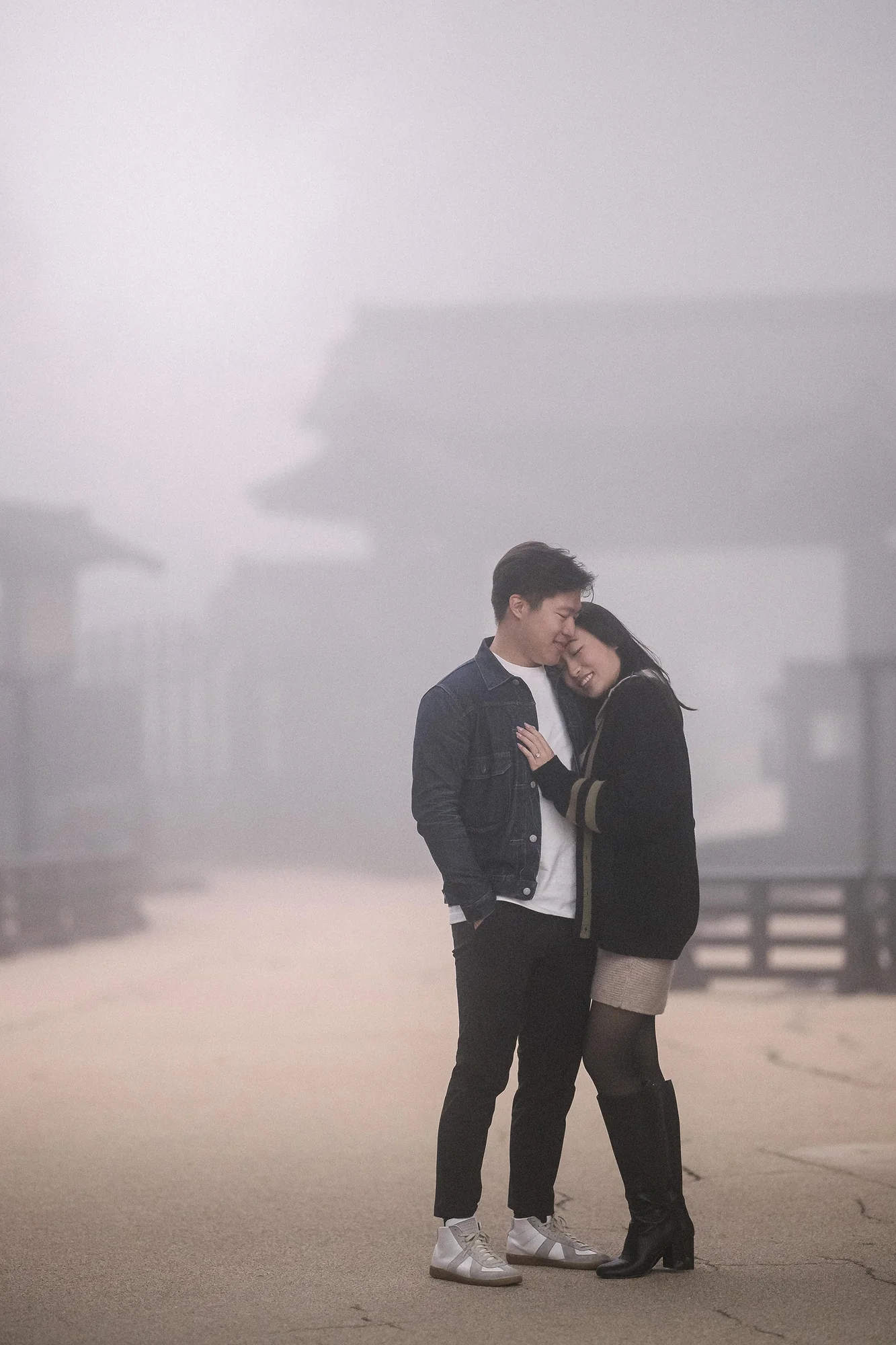 A couple hold each other in the mist beside the old checkpoint gate in Hakone.
