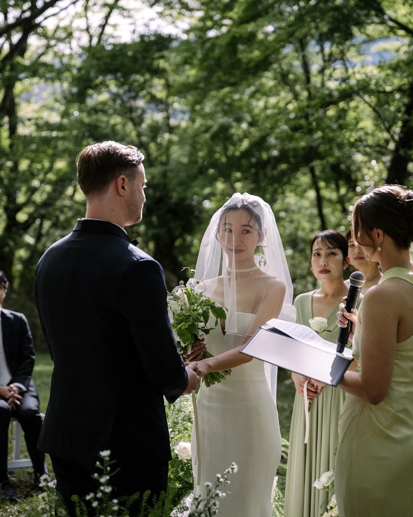 The bride reads her vows to the groom beside her bridesmaids at a forest ceremony in Hakone.