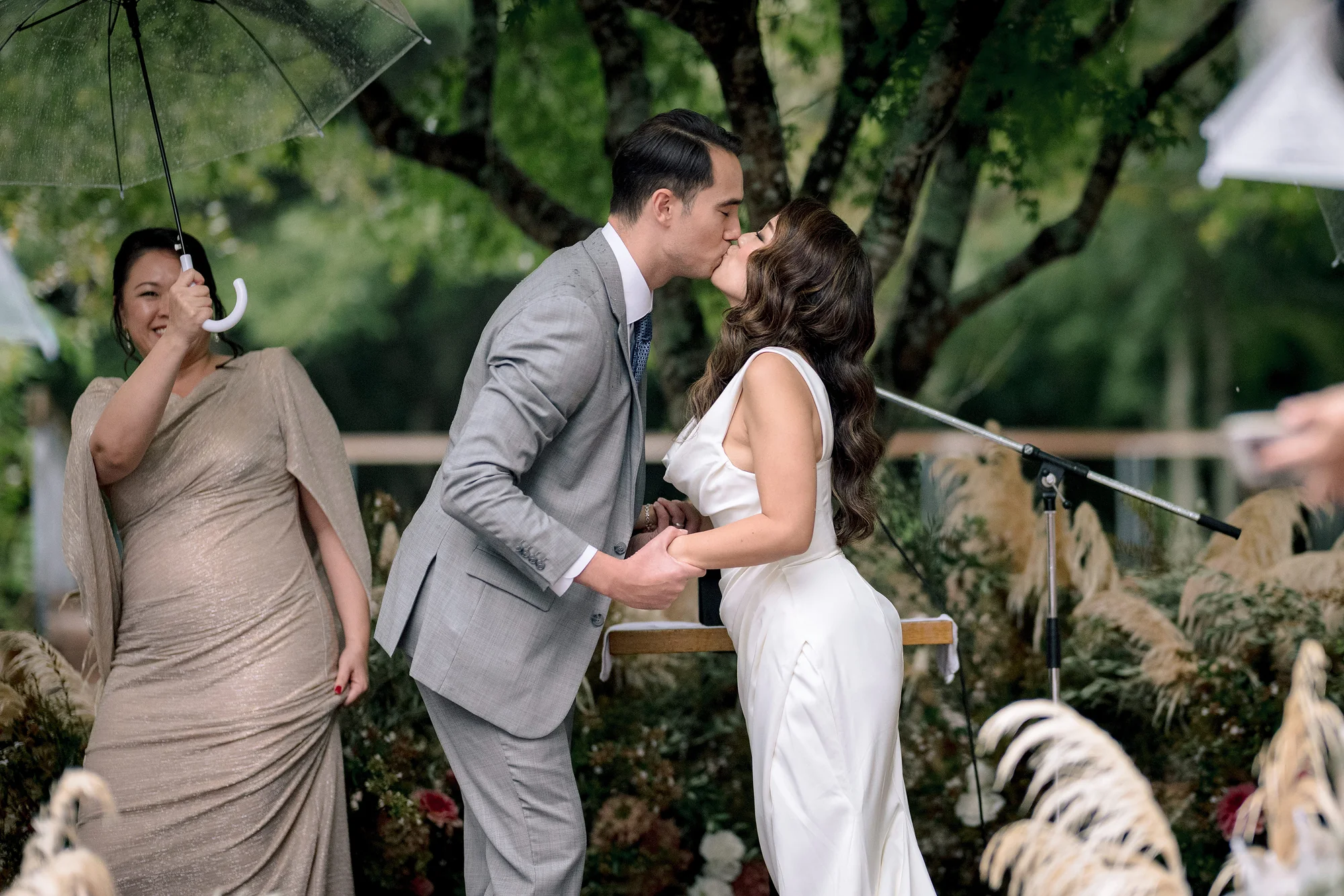 The groom kisses the bride at the close of their ceremony as a bridesmaid smiles beside them in Hakone.