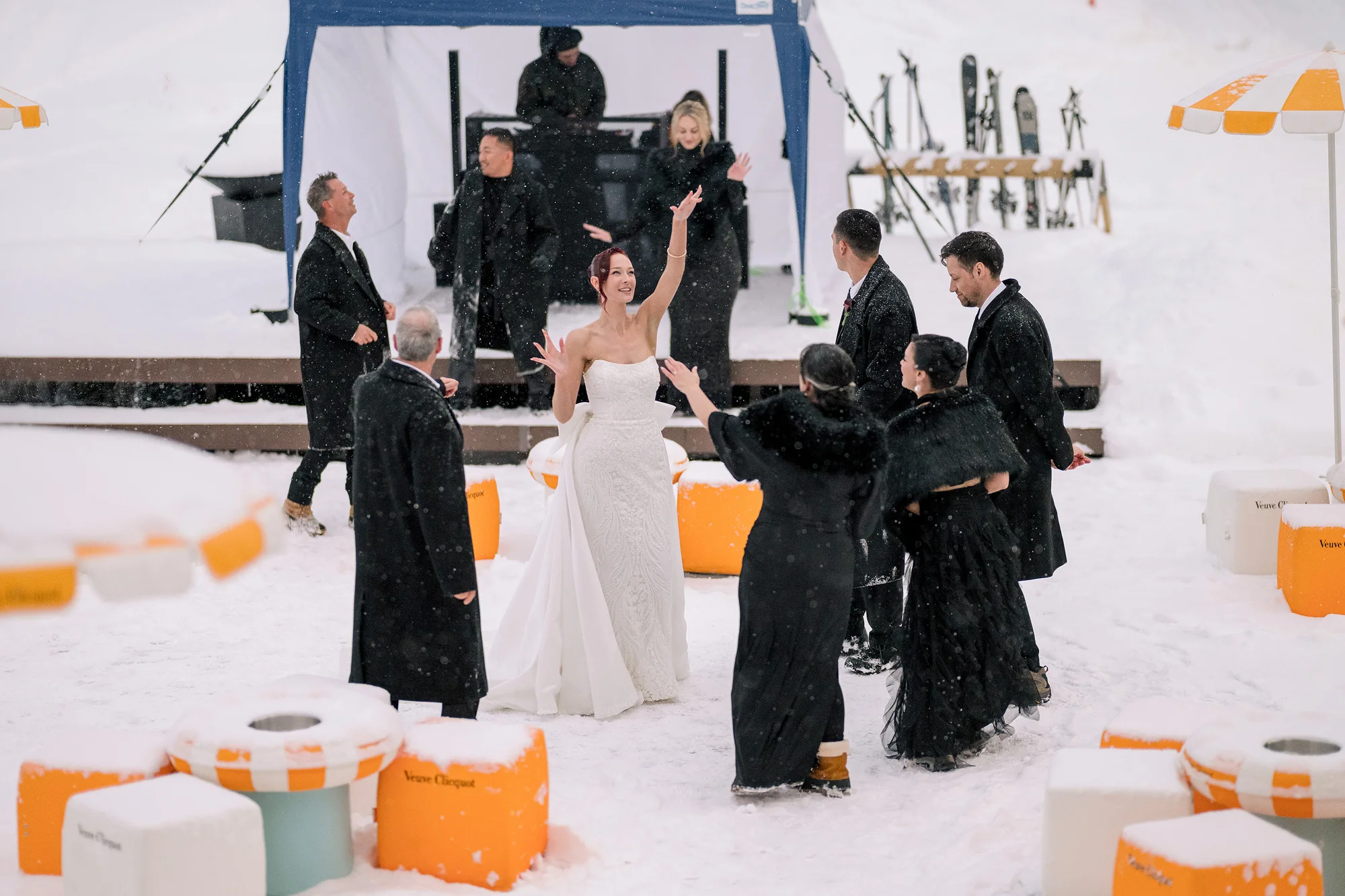 The bride dances with friends in the snow outside a mountain lodge.