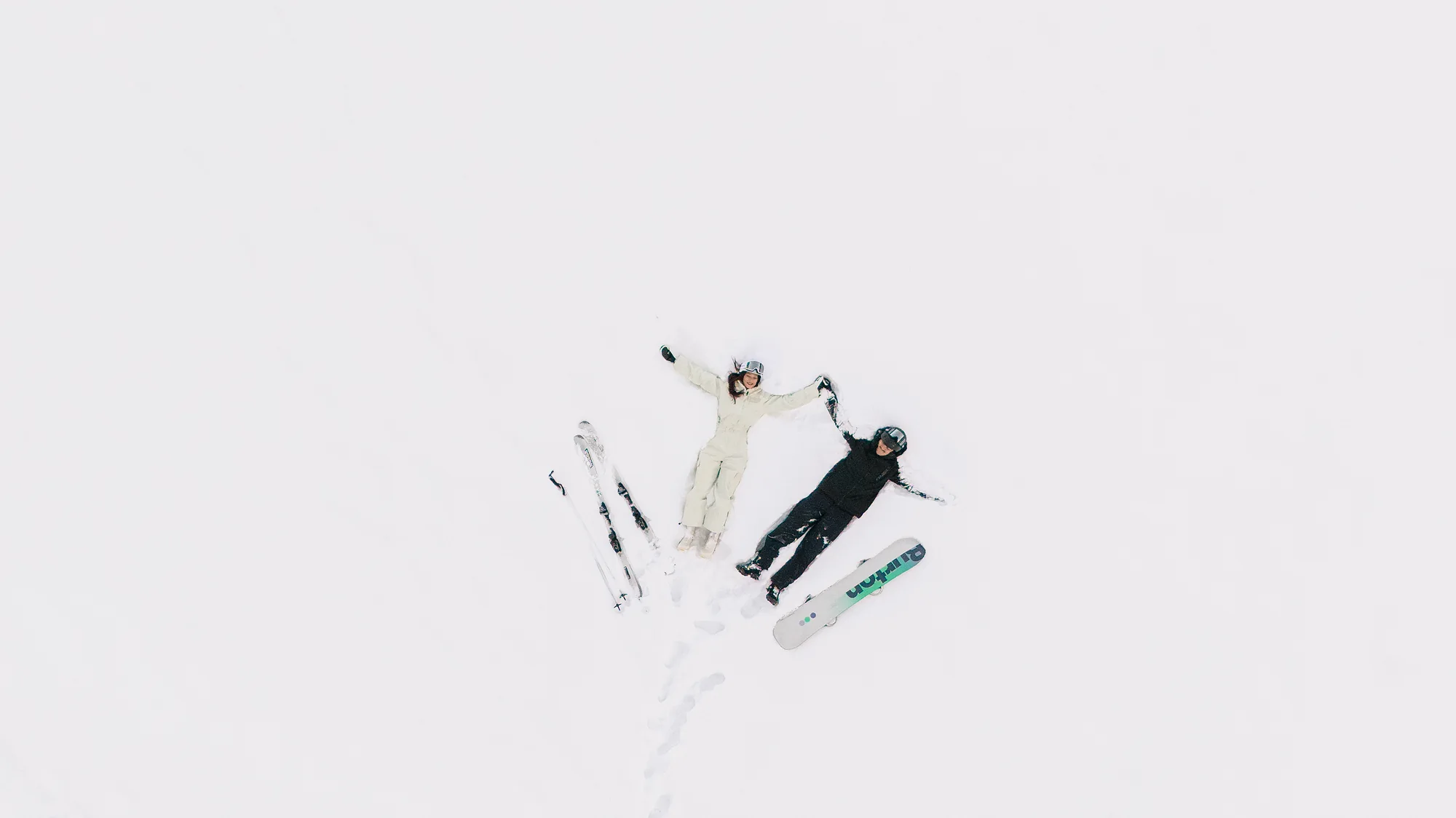 From above, the couple ski side by side across an unbroken field of snow.