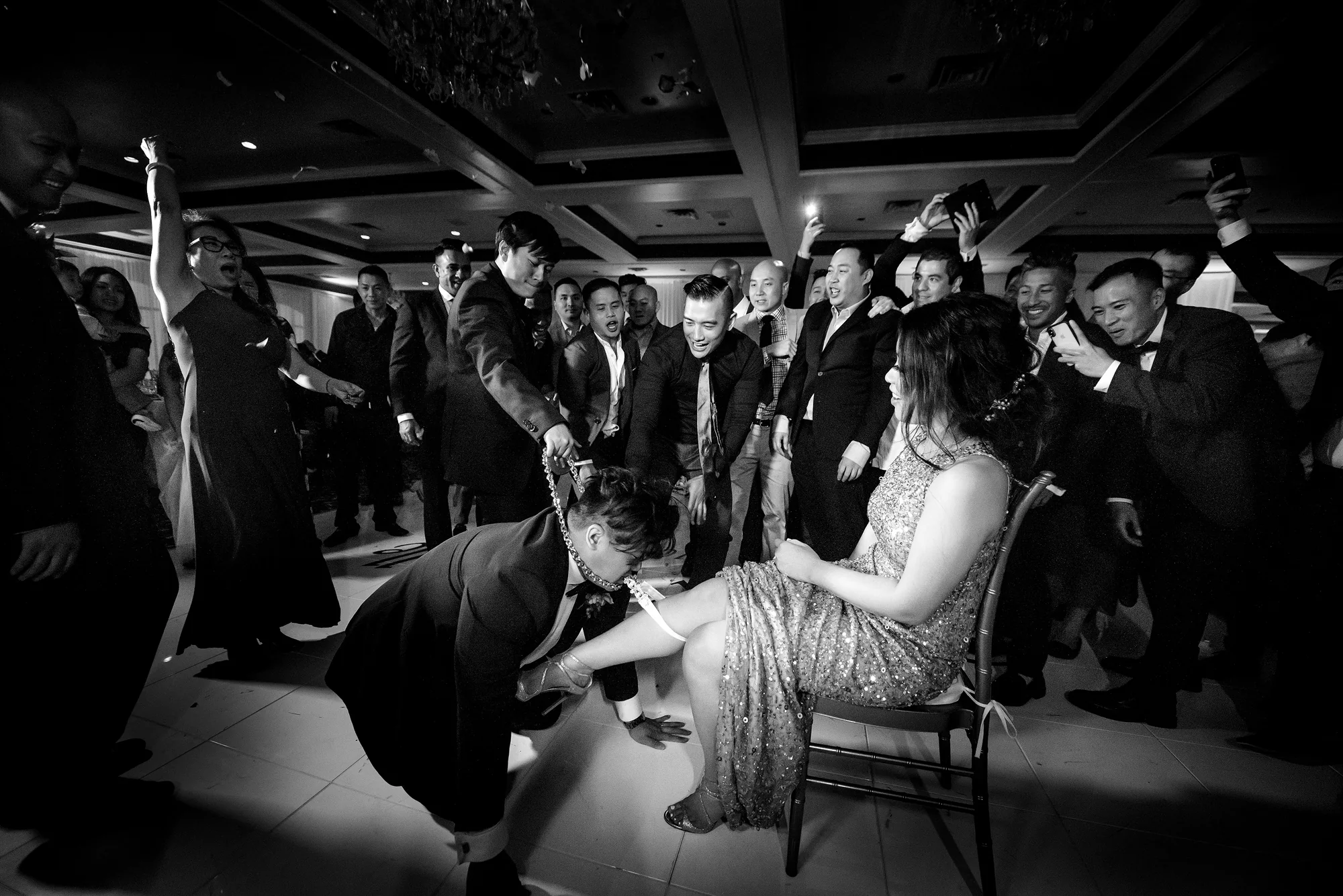 In black and white, guests dance and cheer around the couple on a crowded dance floor in Houston.