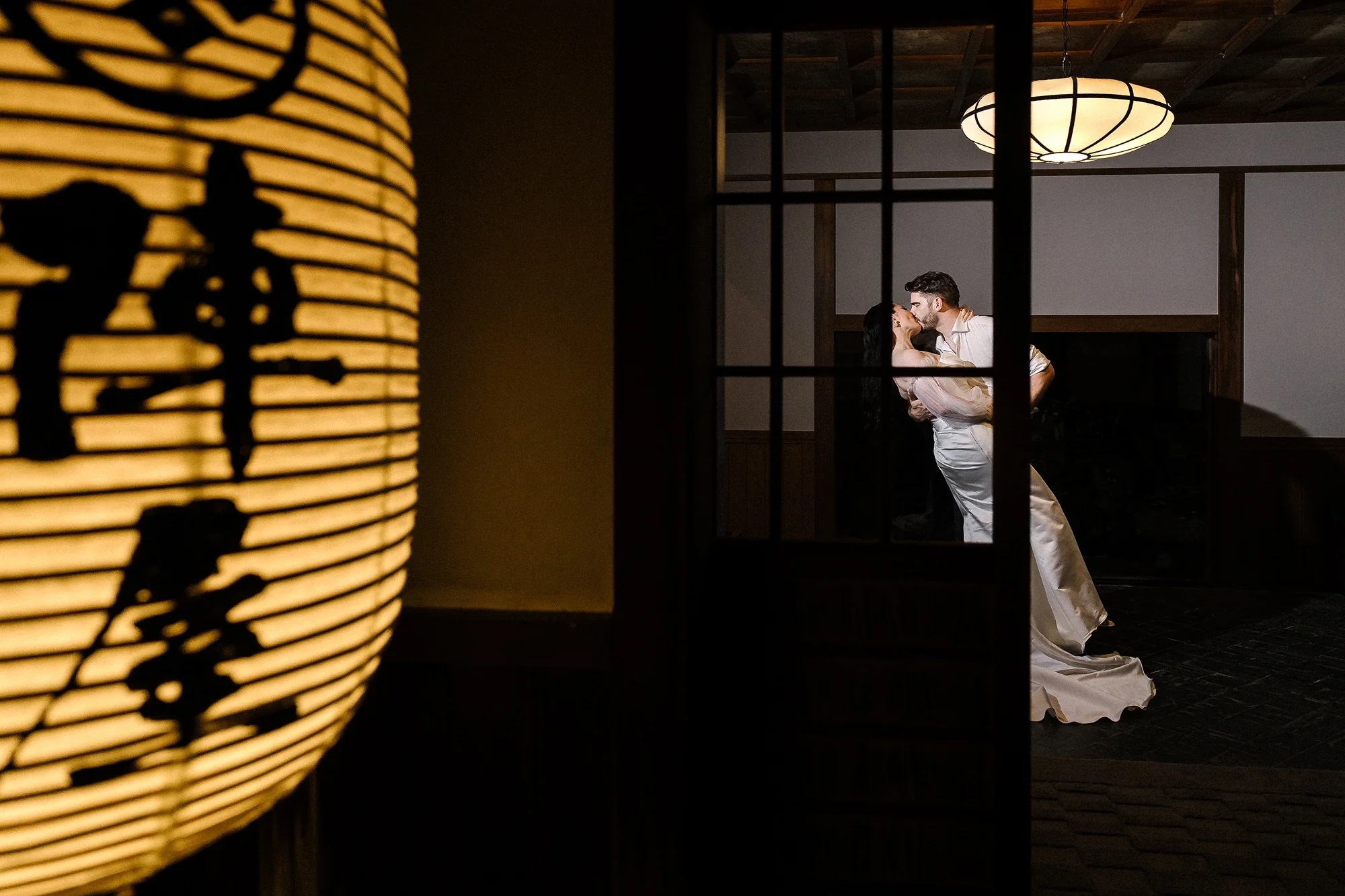 A couple framed by a glowing paper lantern at night.
