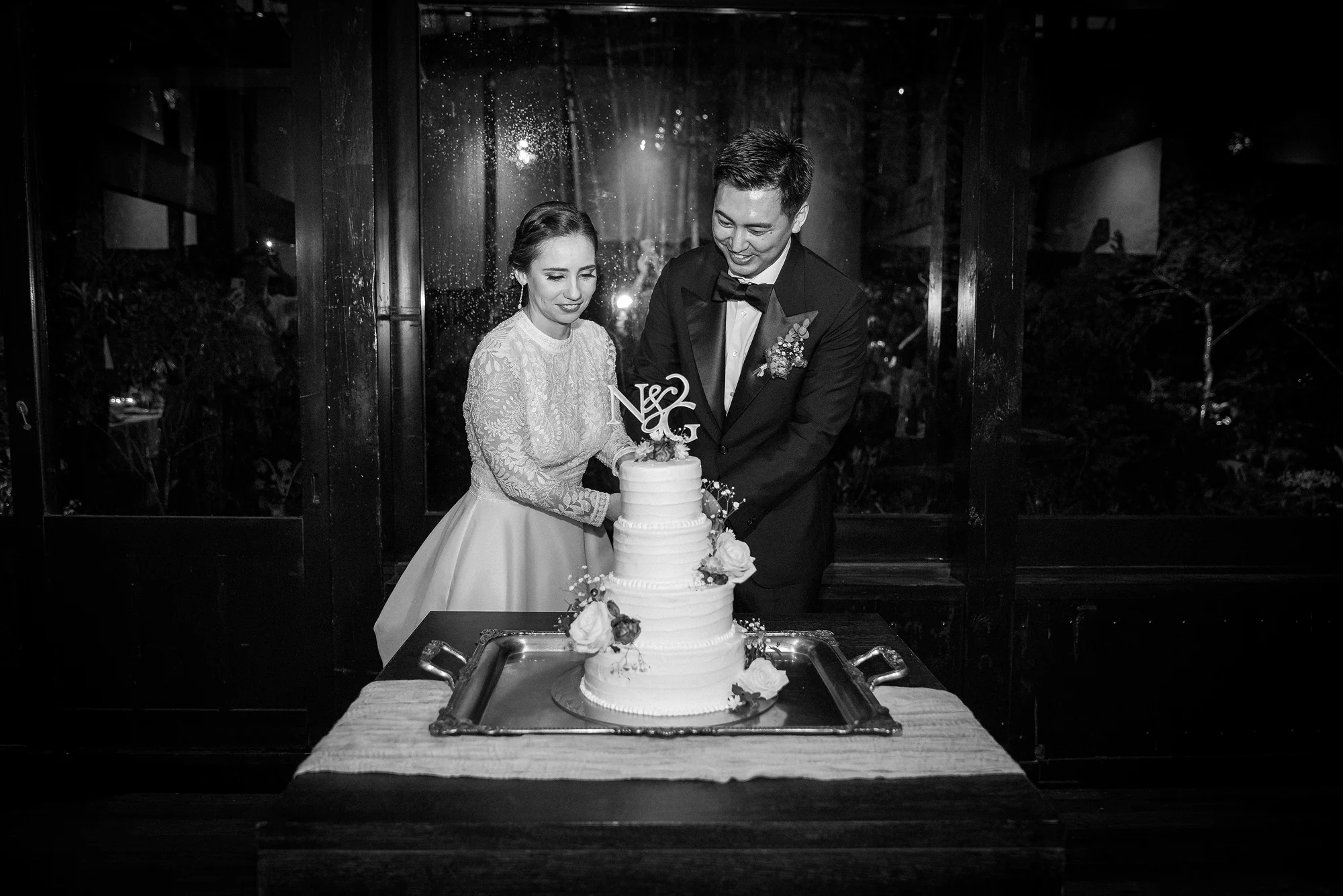 Bride and groom cutting a tiered wedding cake during their Jinya reception.