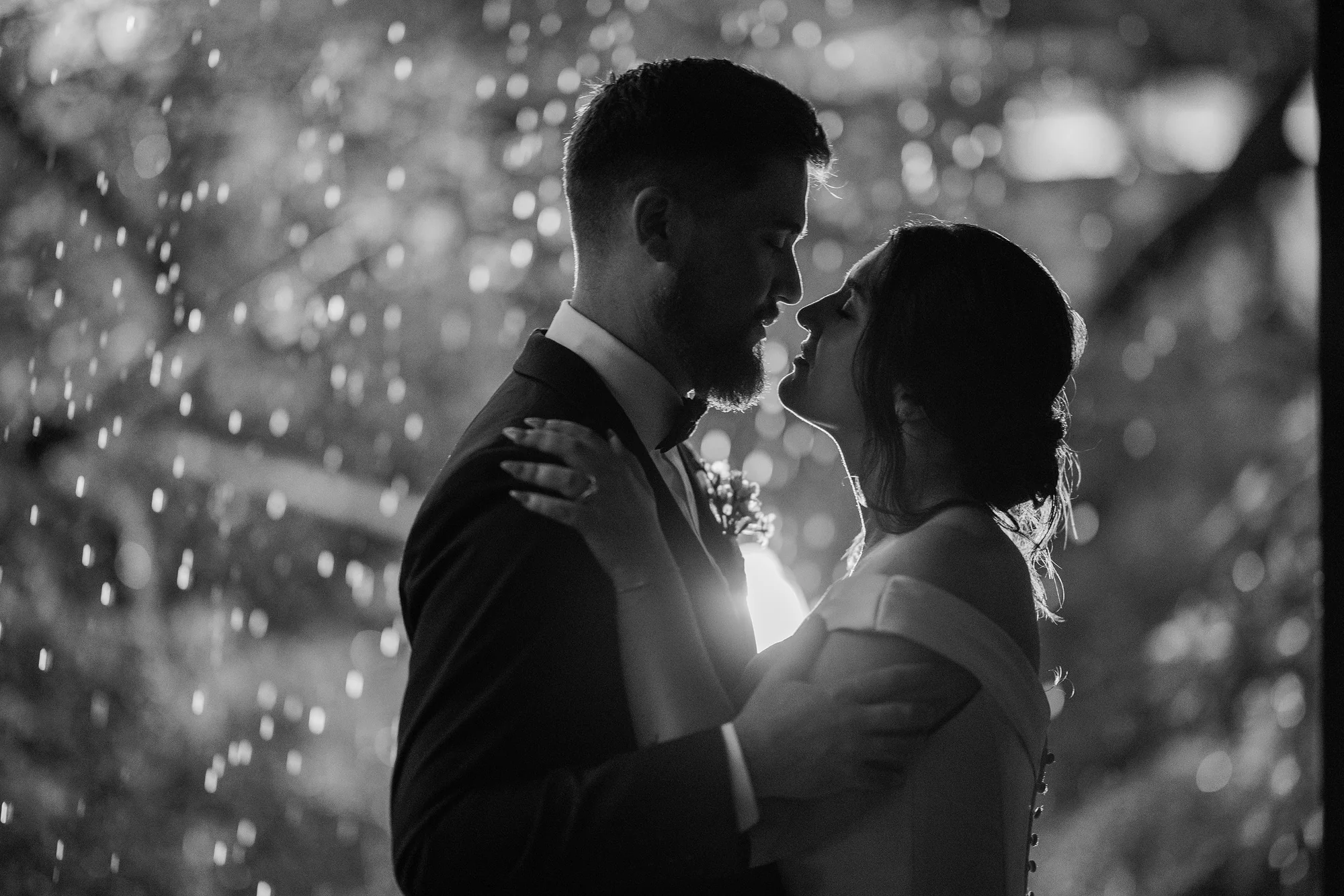 In black and white, the couple stand in silhouette in the rain at night at Jinya.