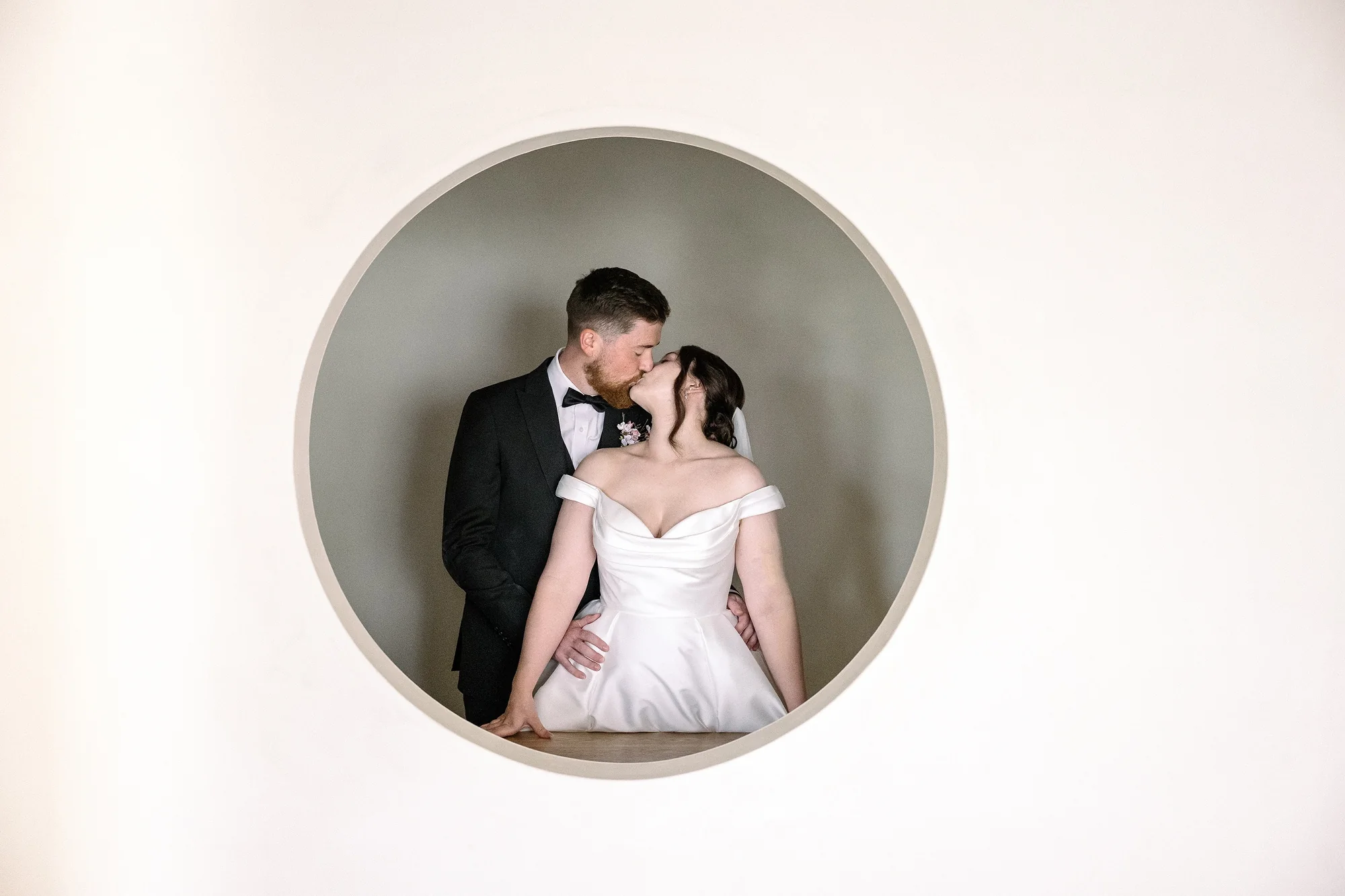 The couple kiss, framed by a round window, at Jinya.