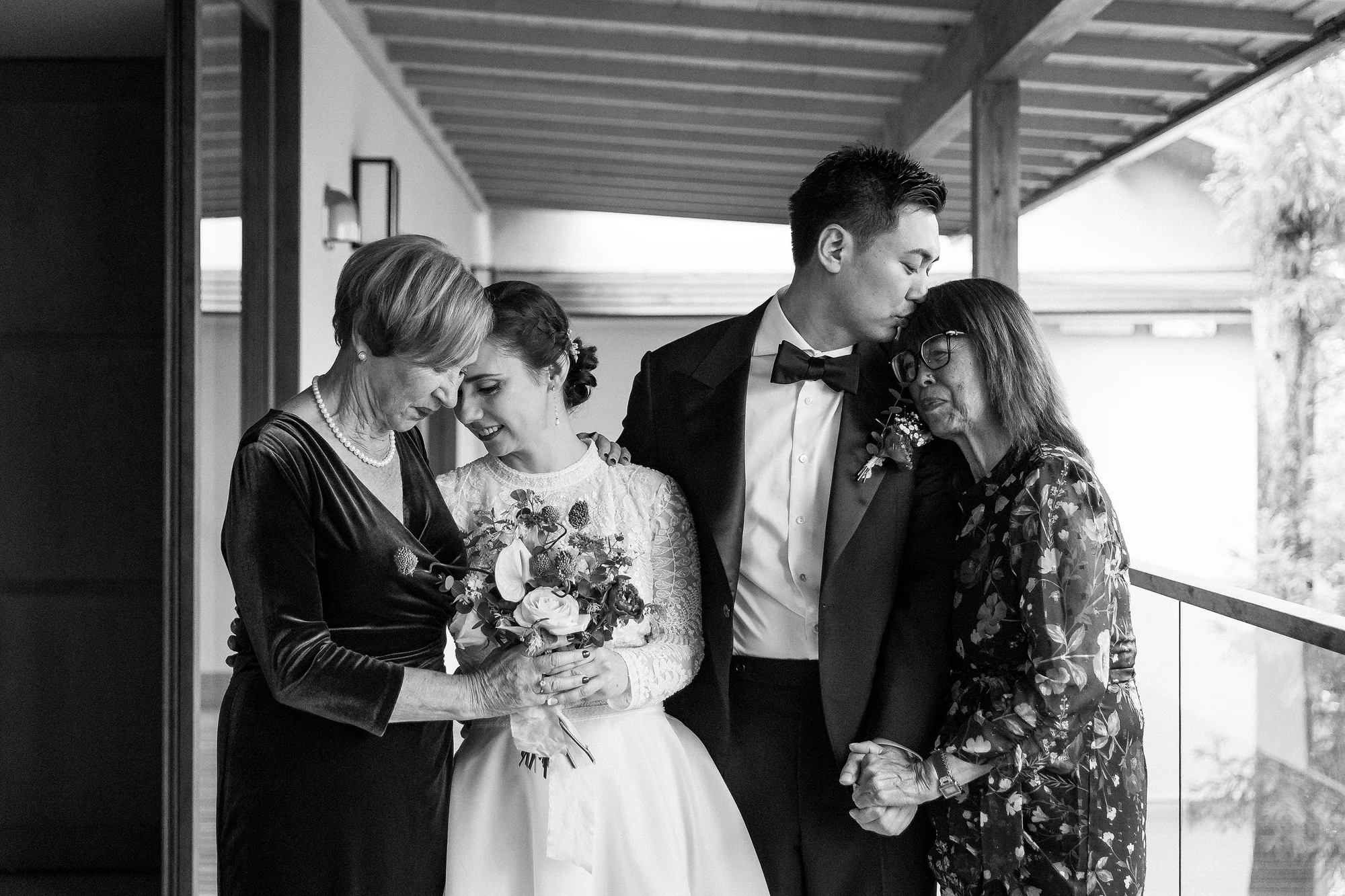 Newlyweds sharing an embrace with their mothers on a ryokan terrace.