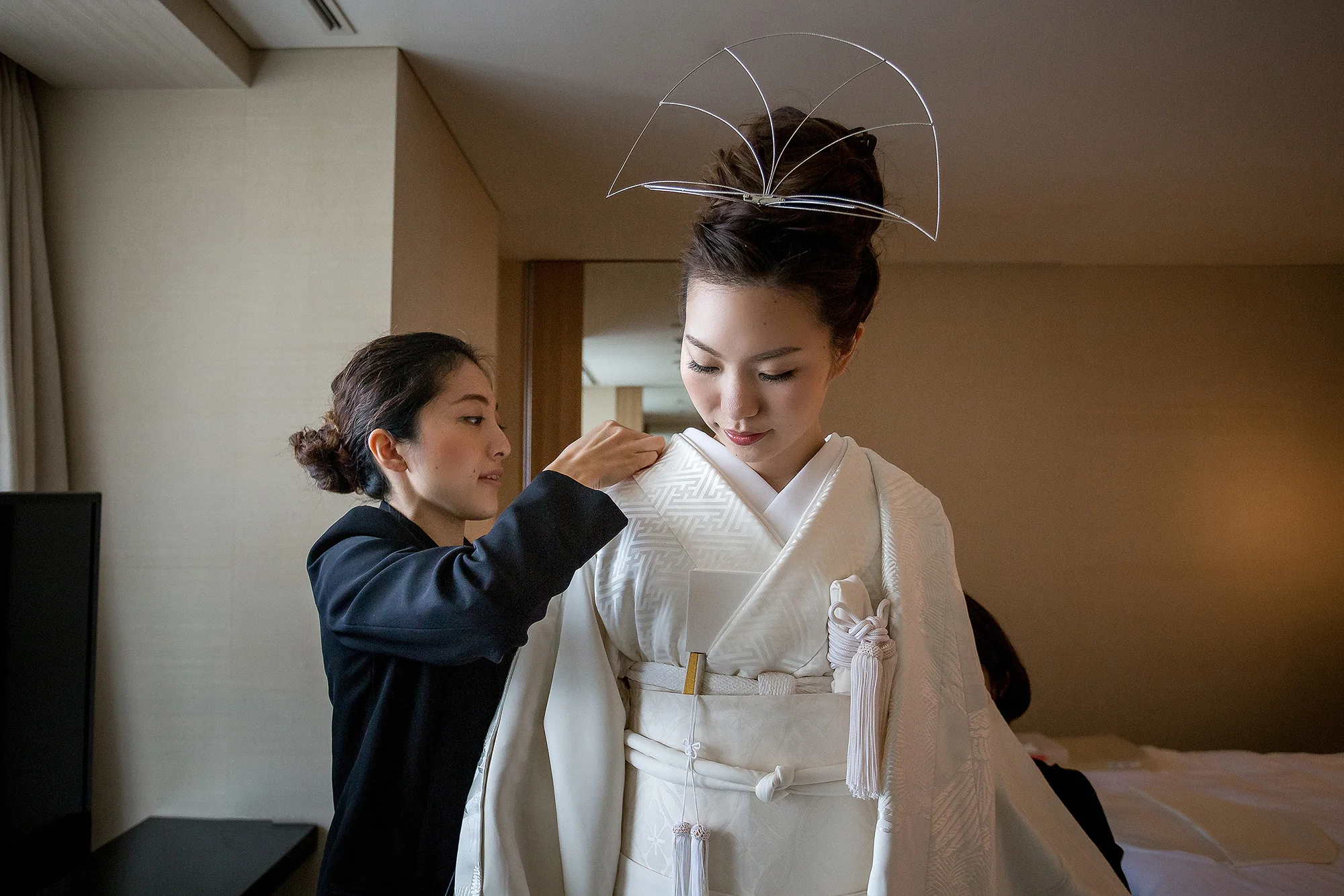 A kitsuke dresser fits the bride's white kimono, a fan of silver wire in her hair.