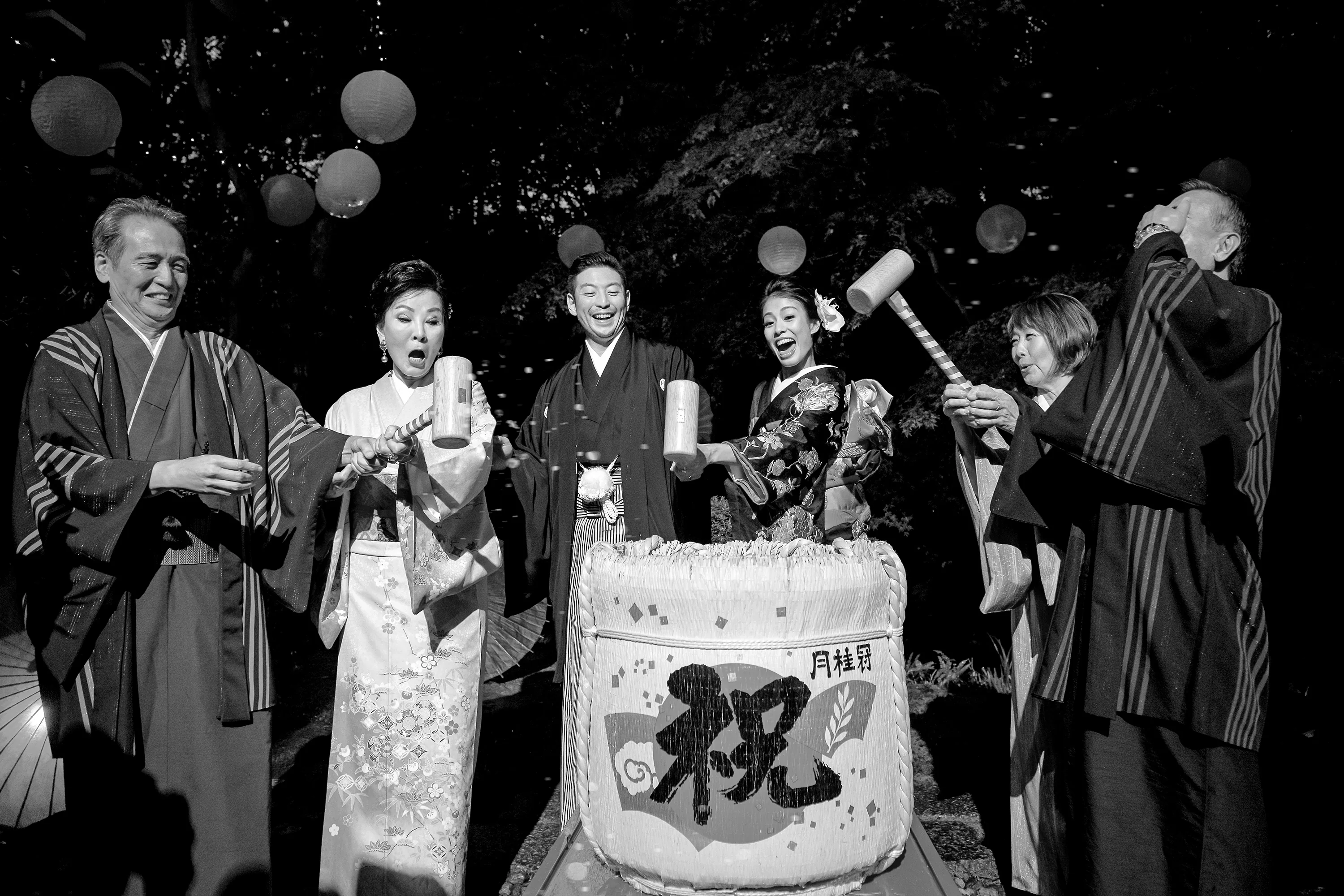 In black and white, the couple and their families break open a sake barrel in the kagami-biraki ceremony in Kyoto.