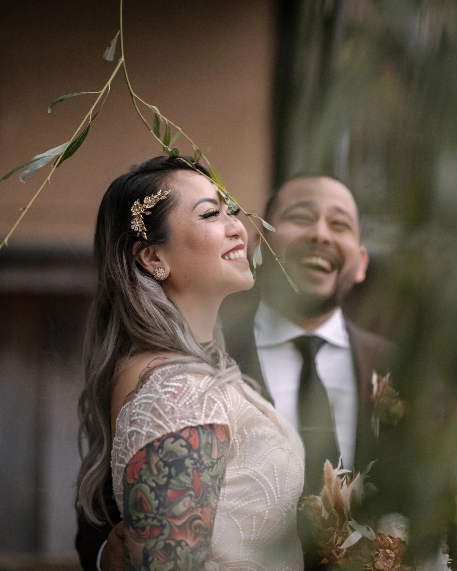 The couple laugh together, seen through willow leaves in Kyoto.