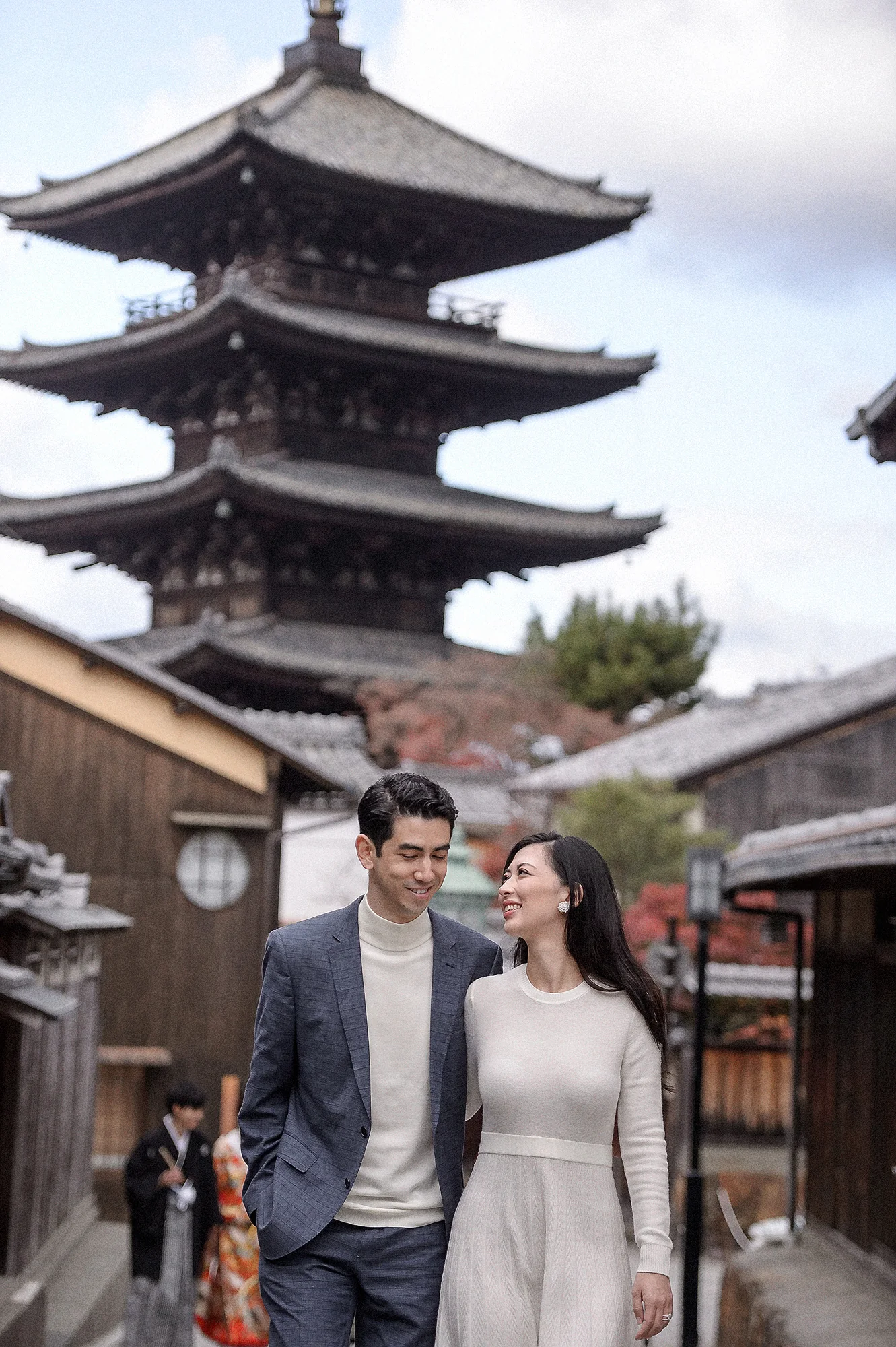 The couple walk down a stone lane below a five-story pagoda in Kyoto.