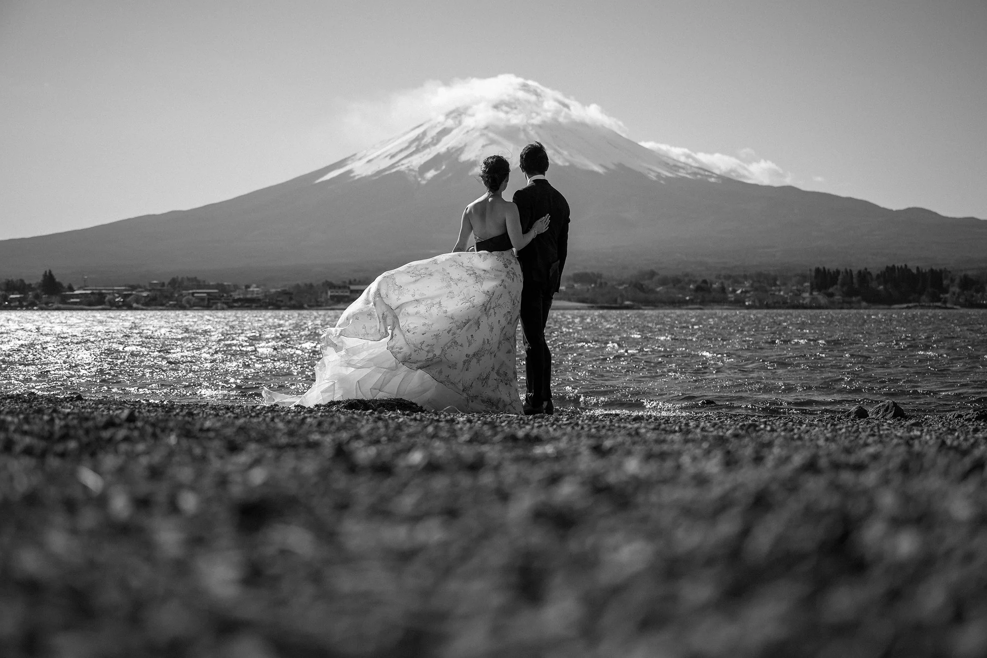 In black and white, the couple stand on the shore of Lake Kawaguchi, the bride's gown lifting in the wind, Mt Fuji behind.