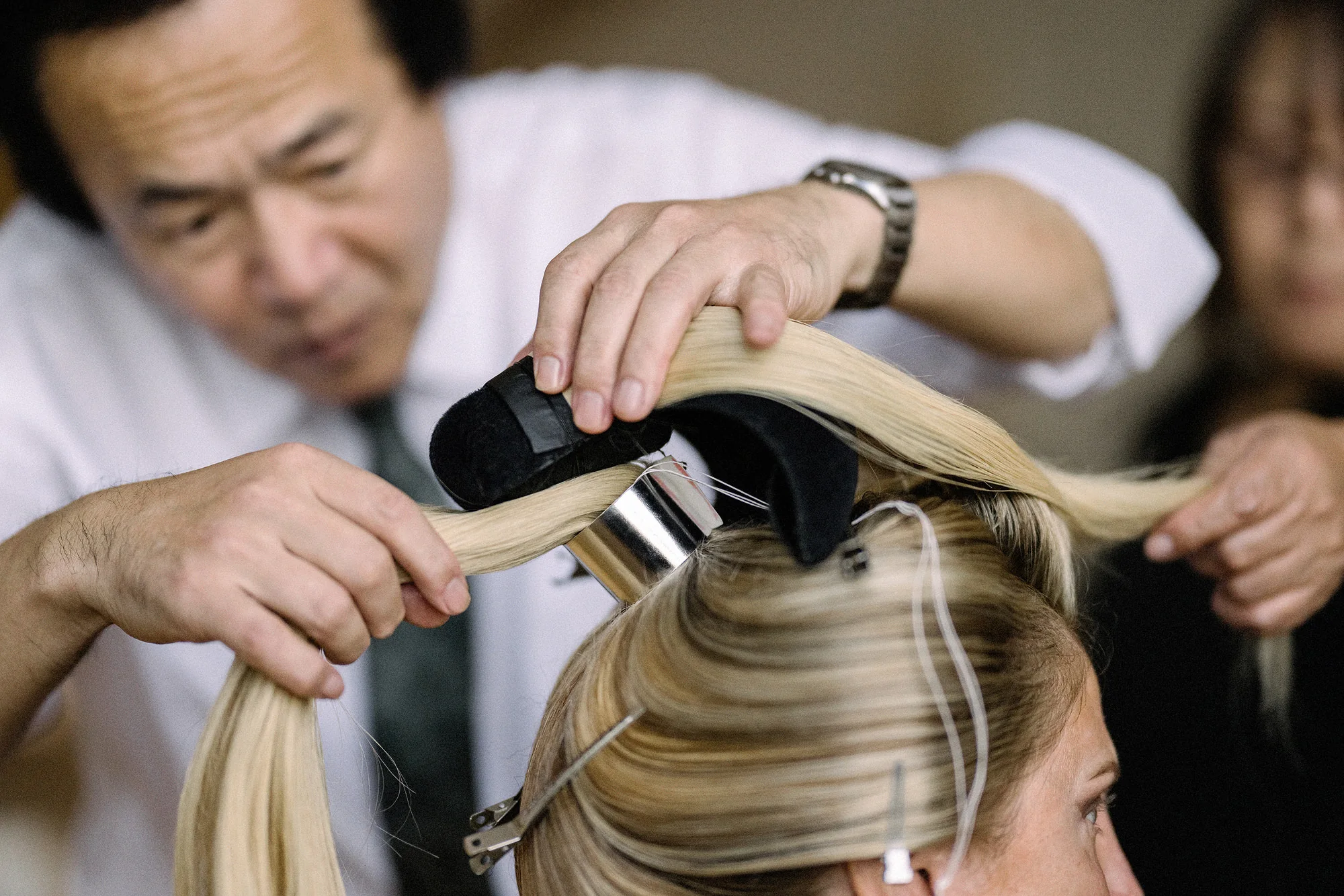 A nihongami master shapes the bride's own hair into a traditional style on the wedding morning.