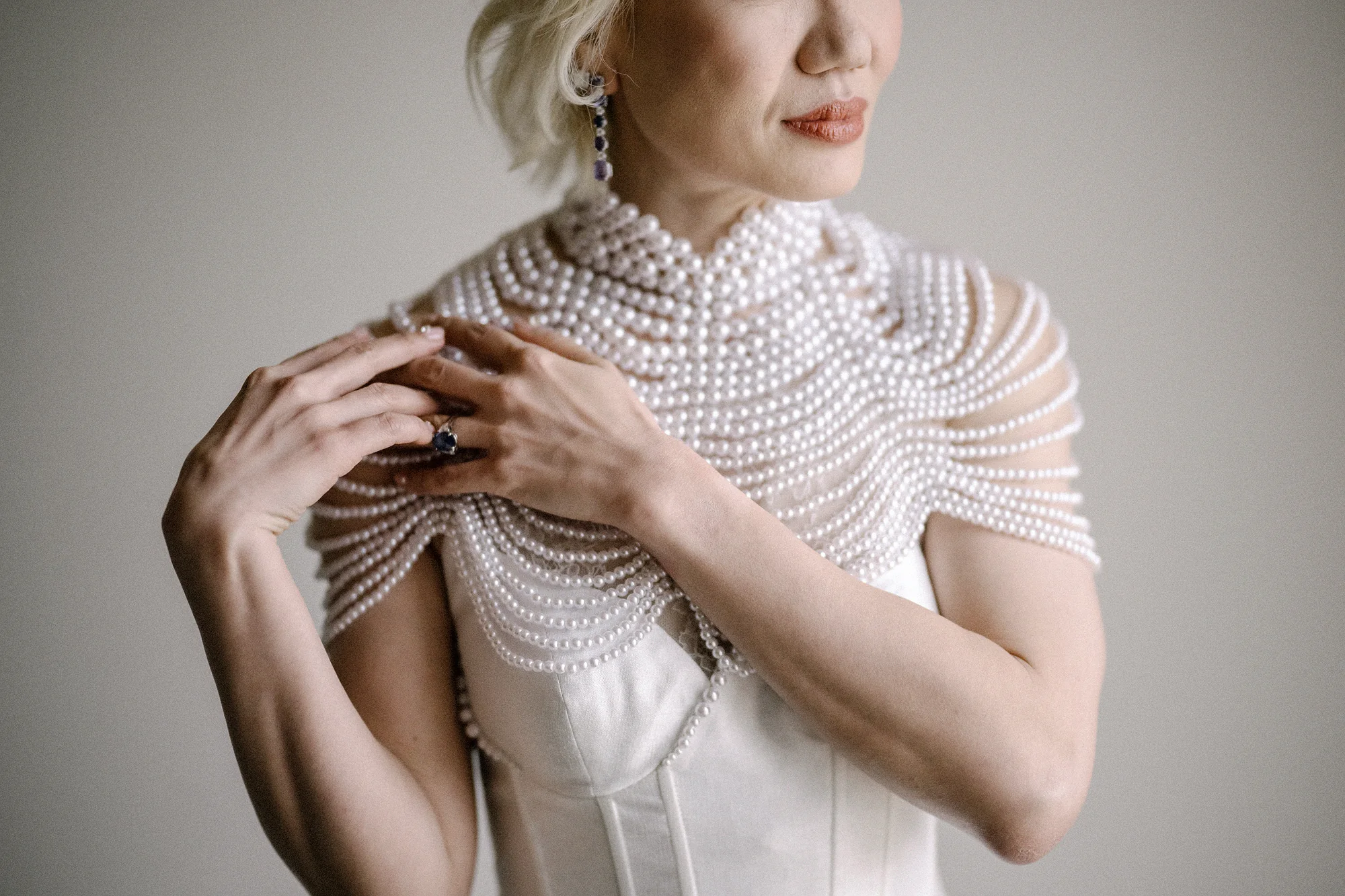 The bride settles a cape of pearls across her shoulders as she gets ready in Niseko.
