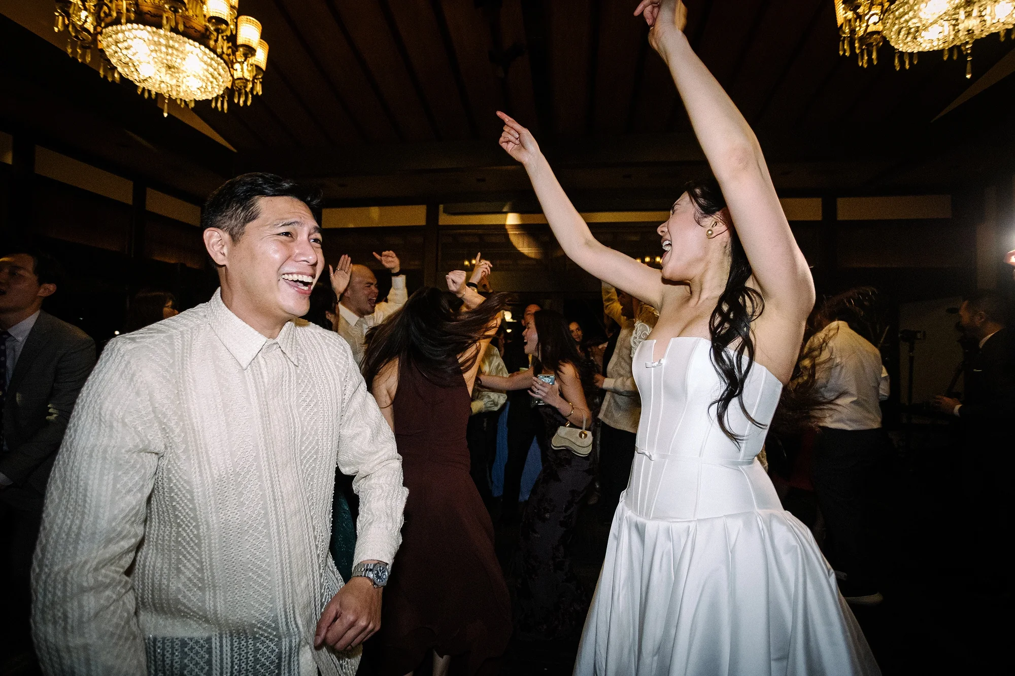 The couple dance at their reception as their guests cheer.