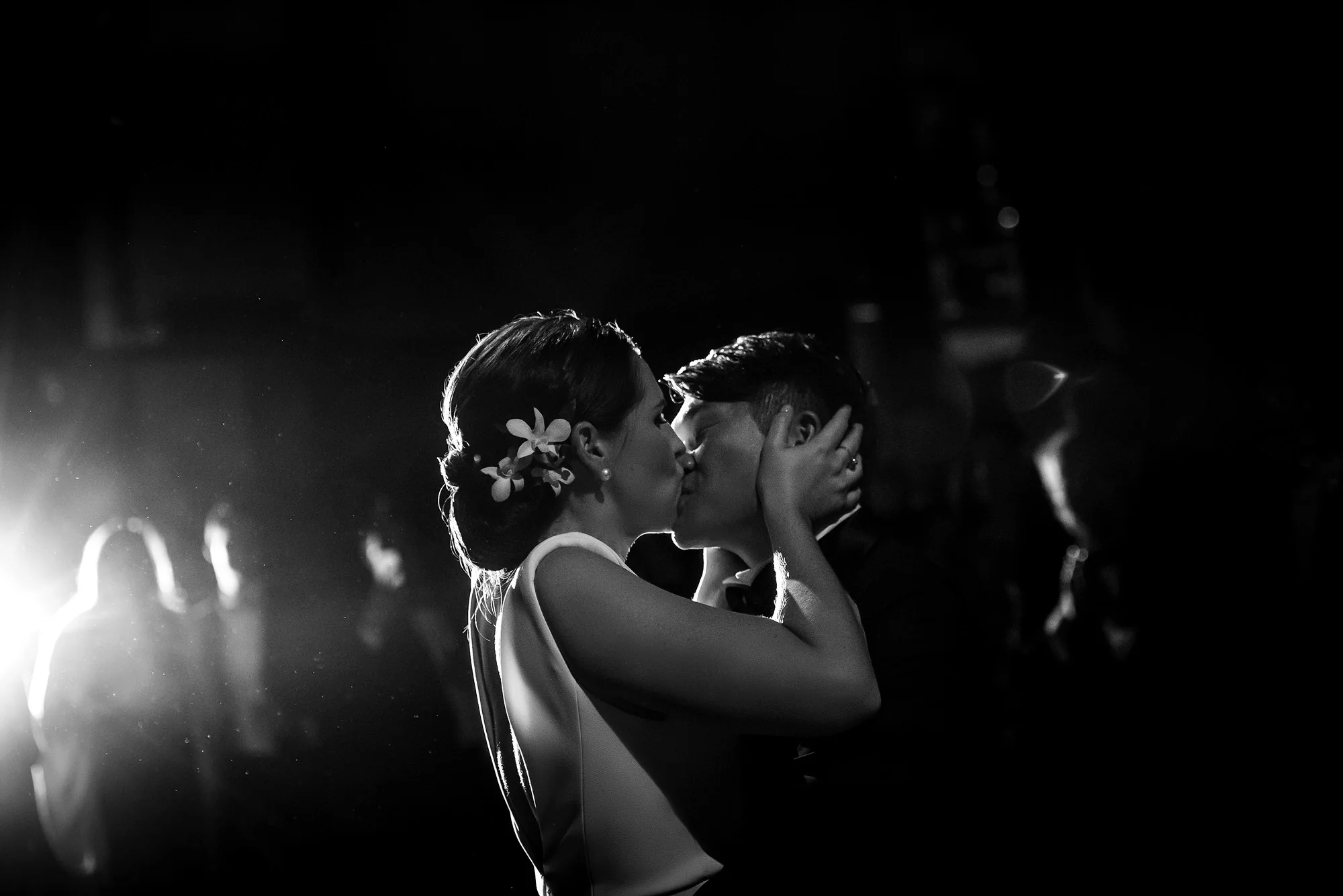 In black and white, the couple kiss on the dance floor as a light flares behind them at the Park Hyatt Tokyo.