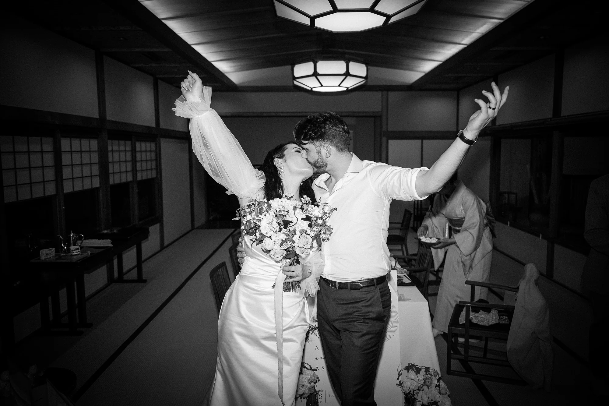 In black and white, the couple make their entrance at dinner, arms raised.
