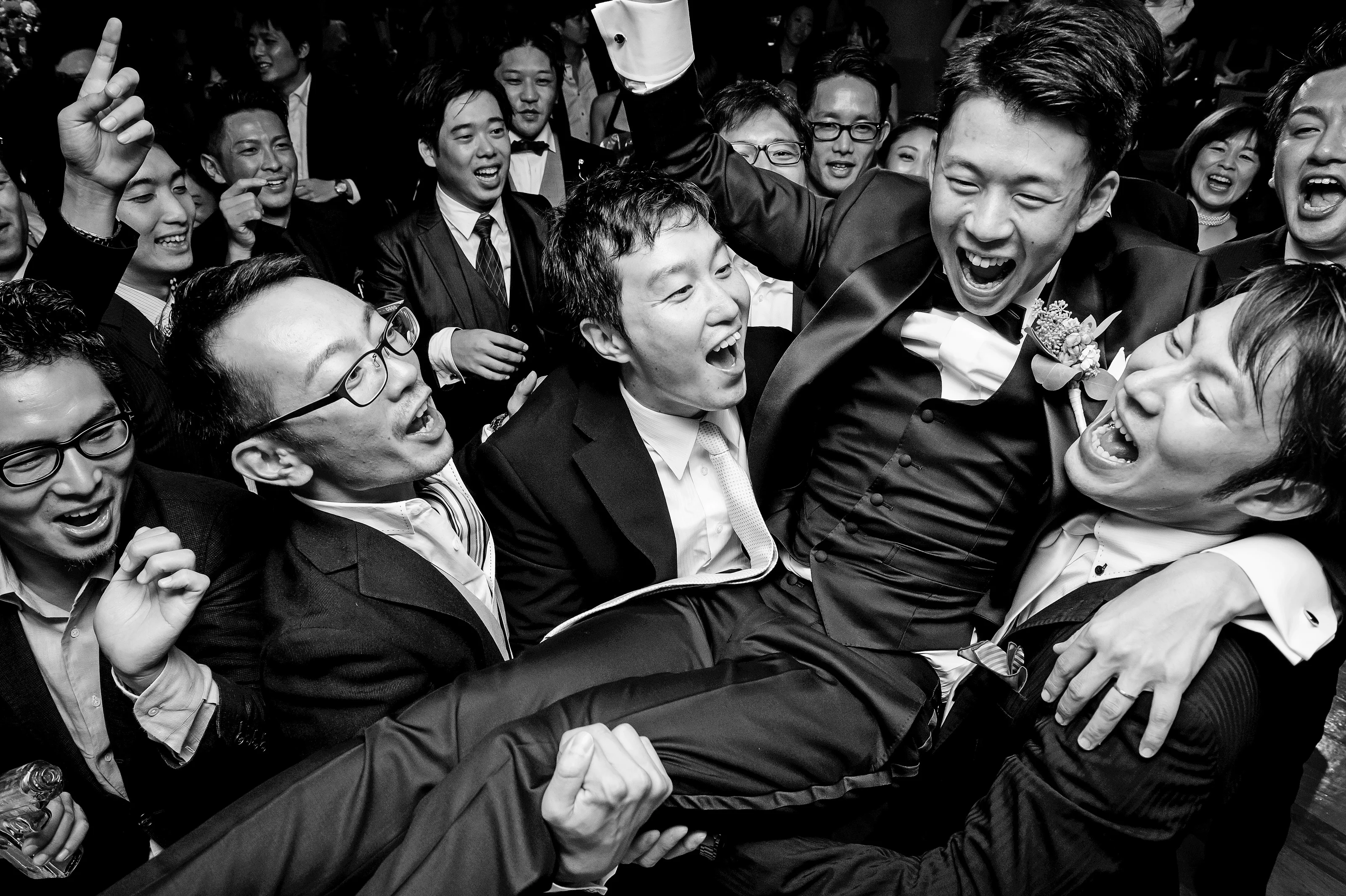 In black and white, the groom is hoisted up by his laughing friends at the Roppongi Hills Club in Tokyo.