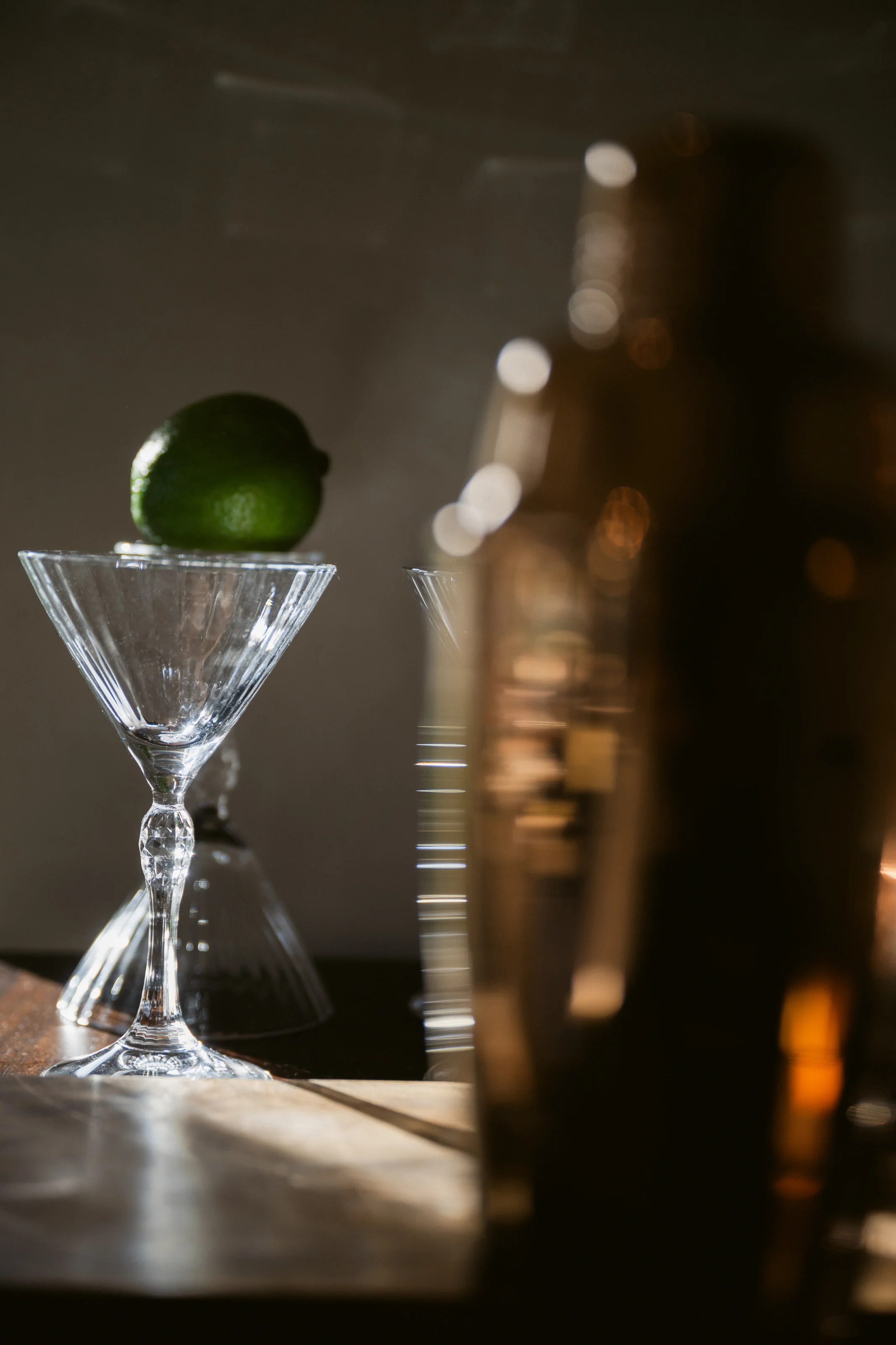 A lime rests on a stemmed cocktail glass at a low-lit bar at Rosewood Miyakojima.