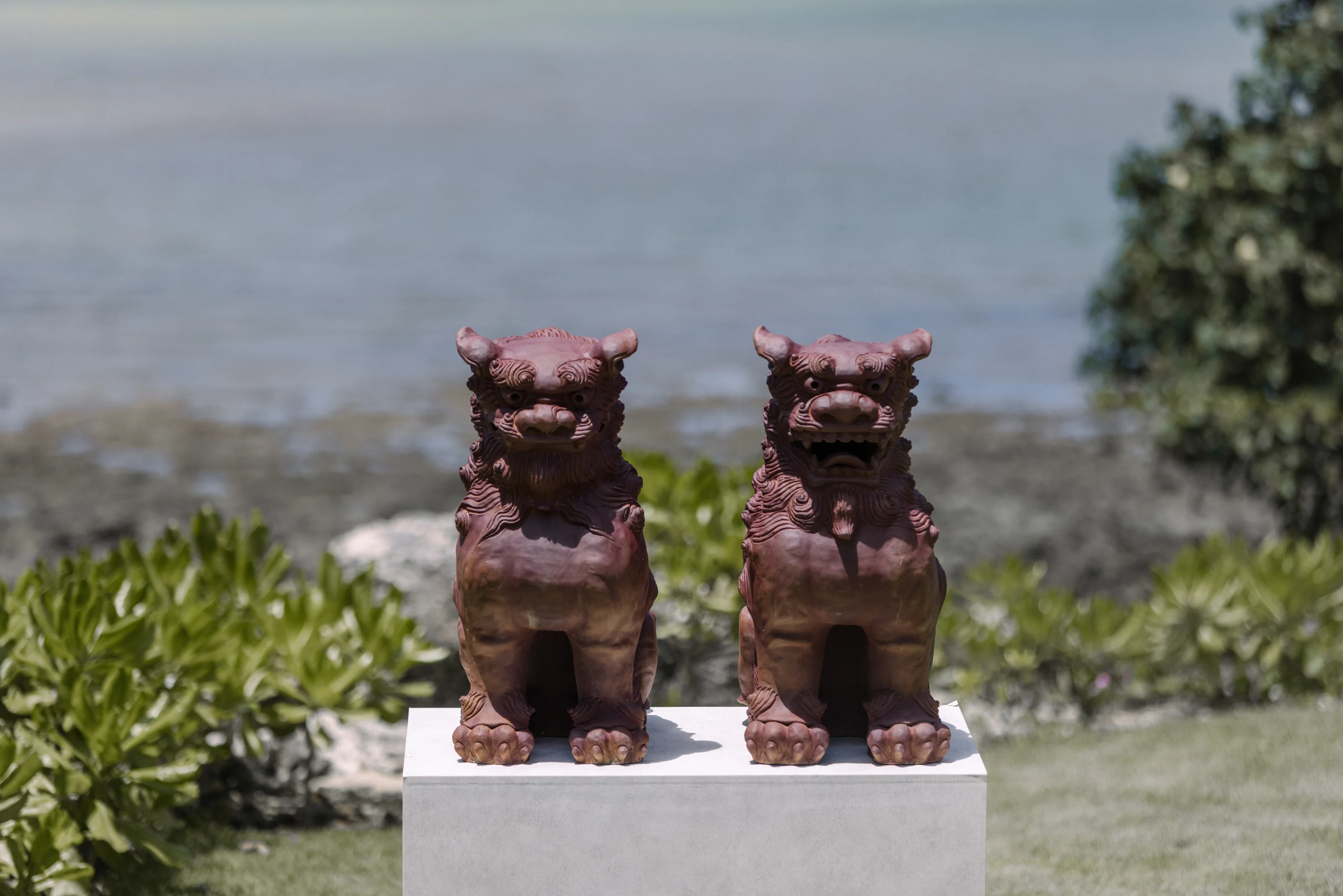 A pair of shisa guardian lions on a plinth above the sea at Rosewood Miyakojima.