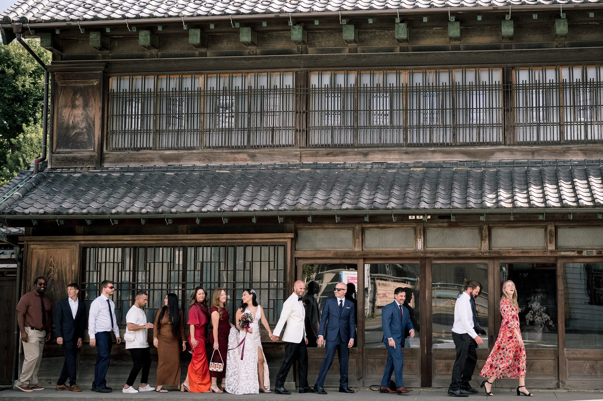 Friends walk arm in arm past the tiled roofs of an old merchant house.