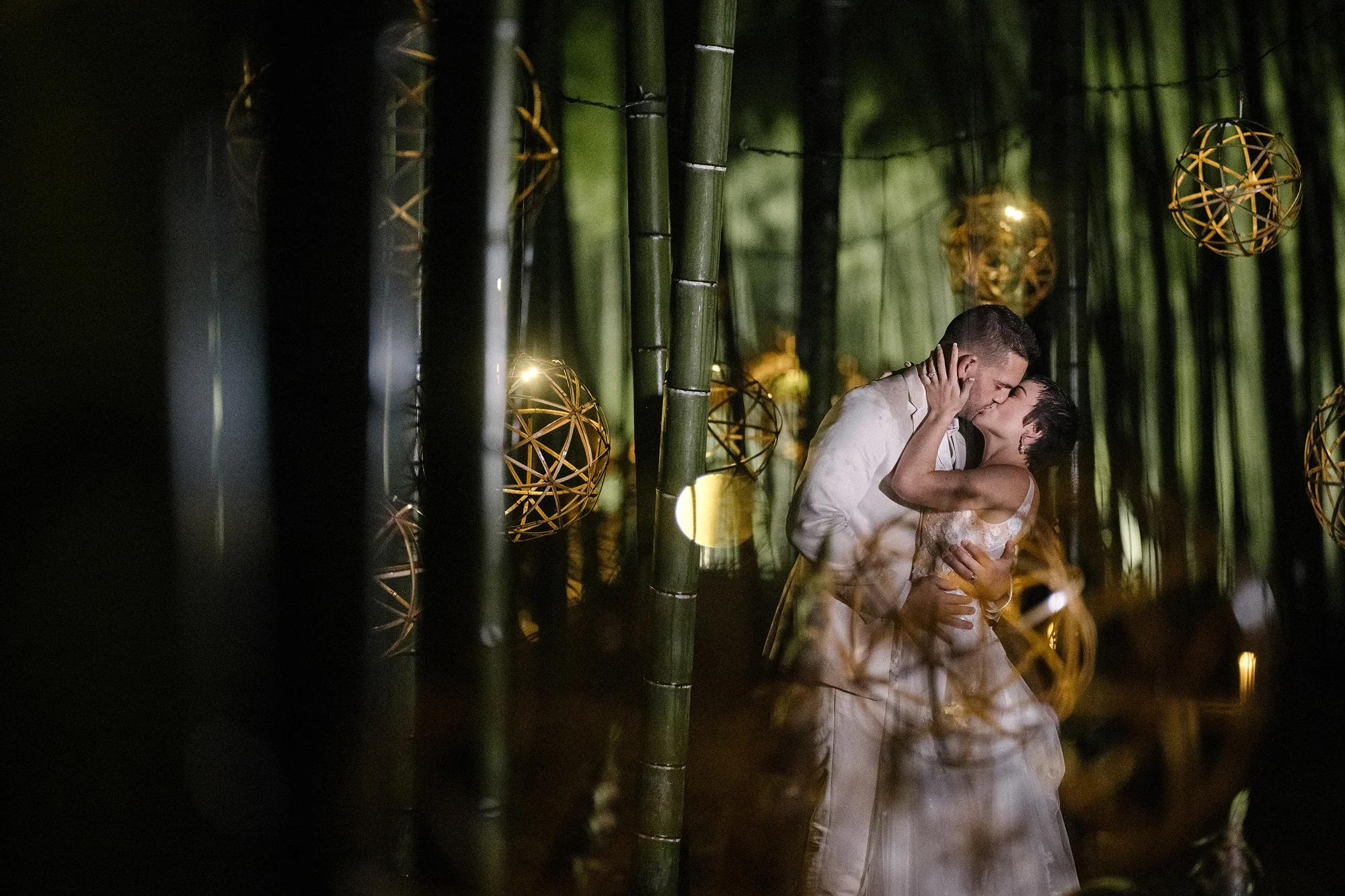 The couple kiss among glowing lights strung through a bamboo grove at night in Tochigi.