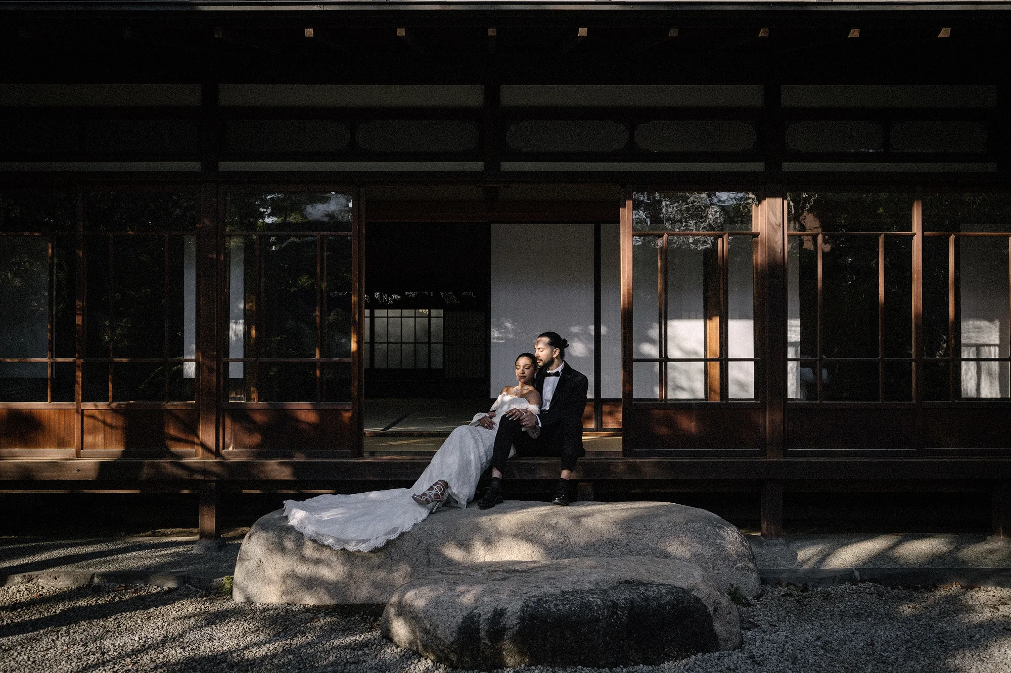 A couple sit on the stepping stones below the veranda of a traditional house in Tokyo.