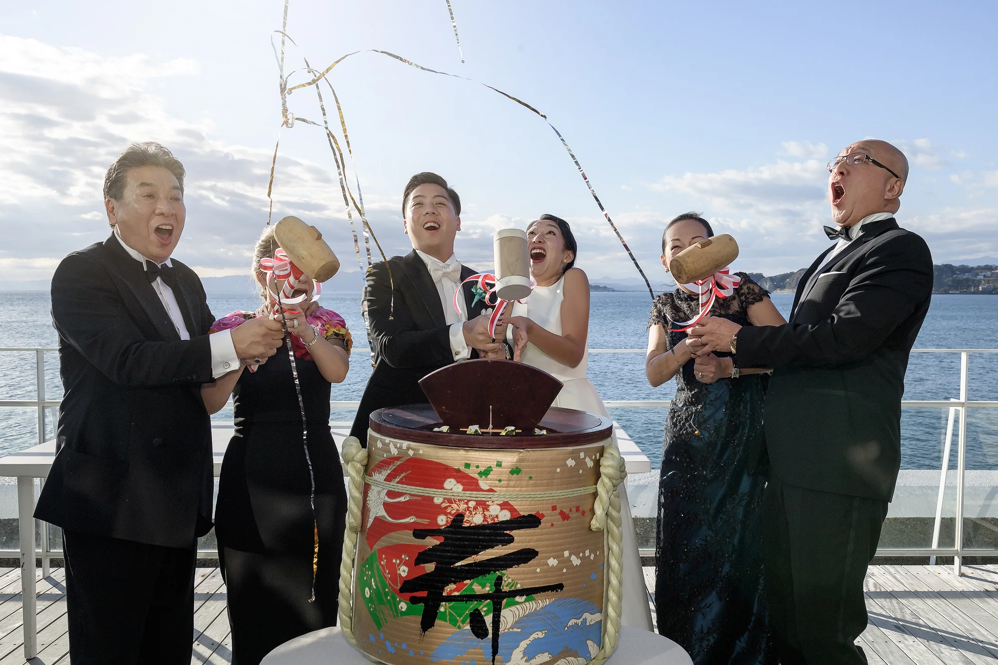 The couple and their parents break open a sake barrel with wooden mallets on a terrace by the sea in Tokyo.