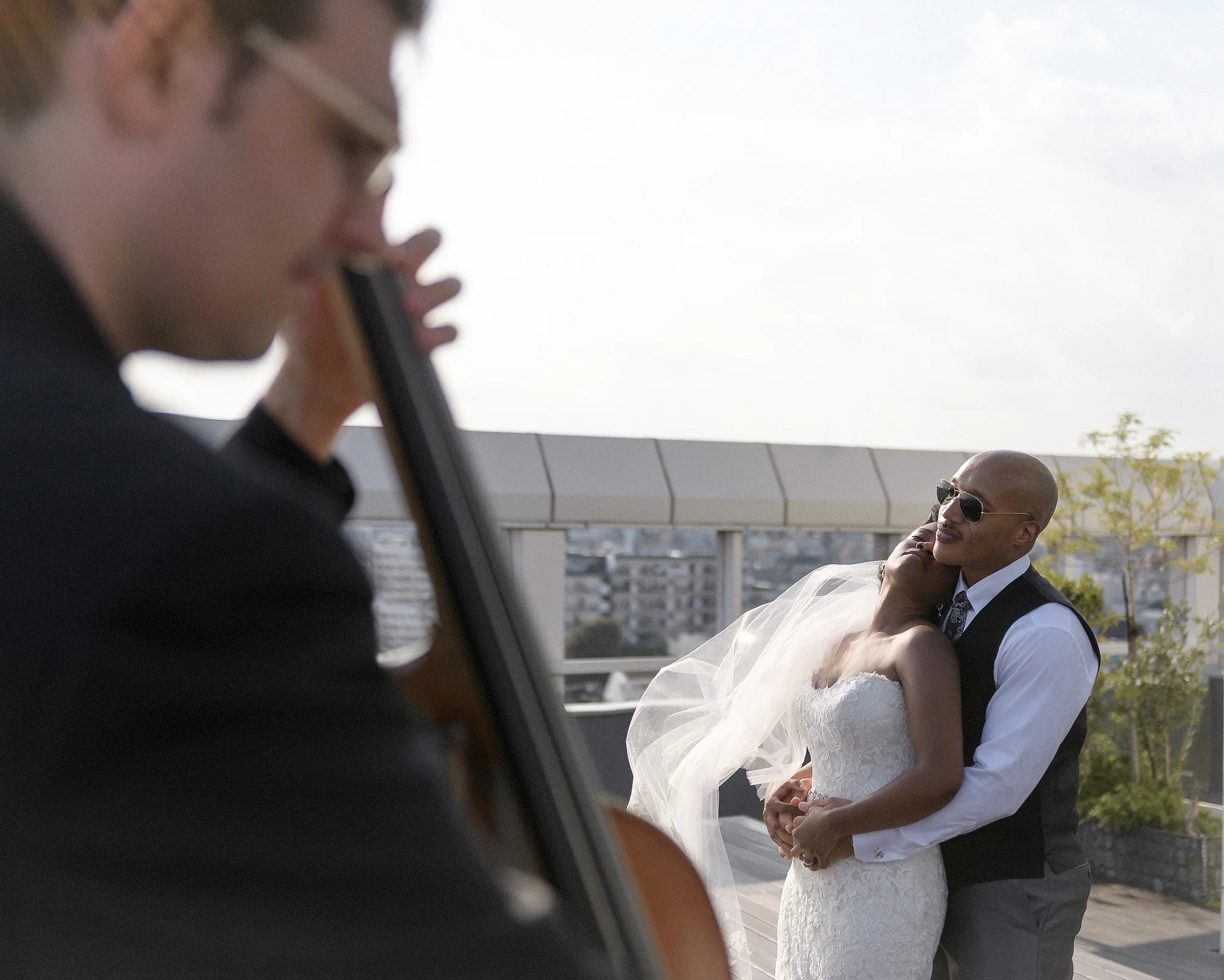 A cellist plays in the foreground as the couple embrace on a rooftop in Tokyo.
