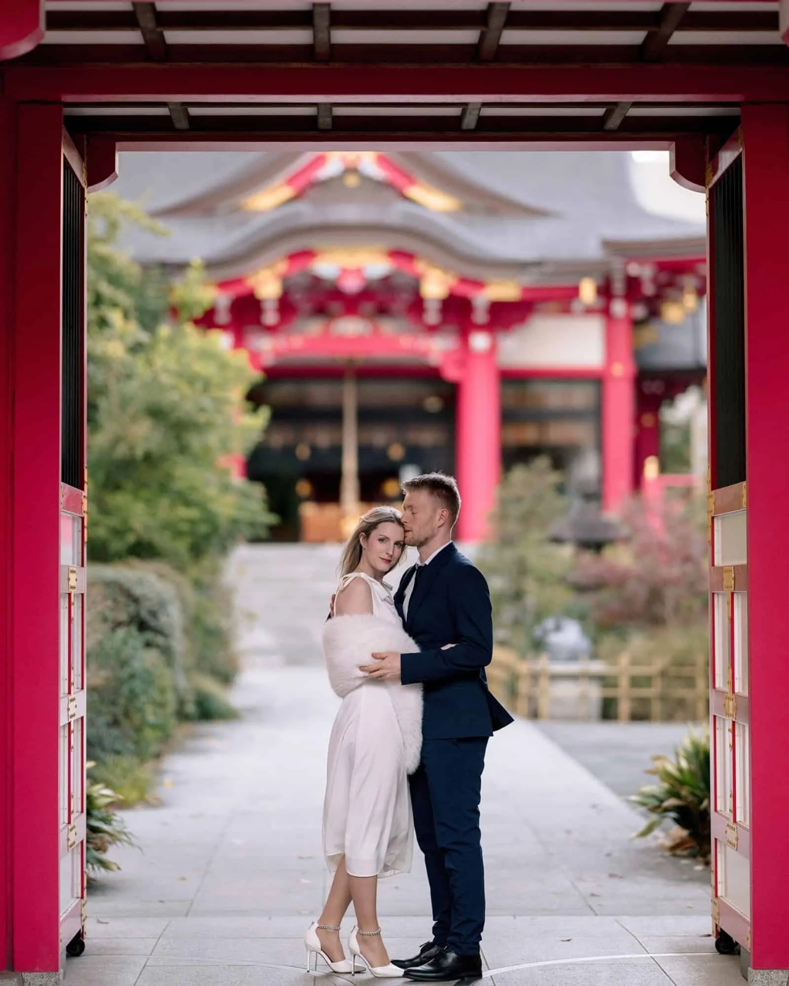 Framed by a vermilion shrine gate, the couple hold each other on the stone path below the hall, a Tokyo pre wedding photoshoot before their elopement.
