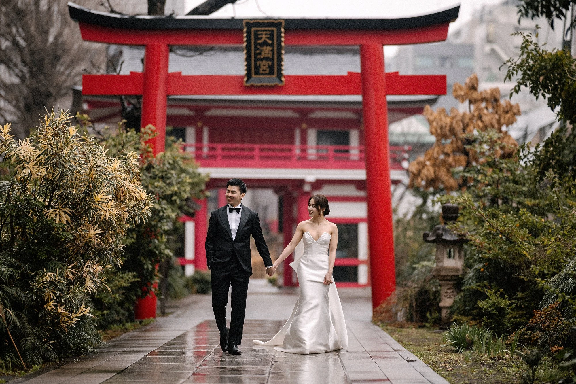 A couple walk beneath a red torii gate in Tokyo.