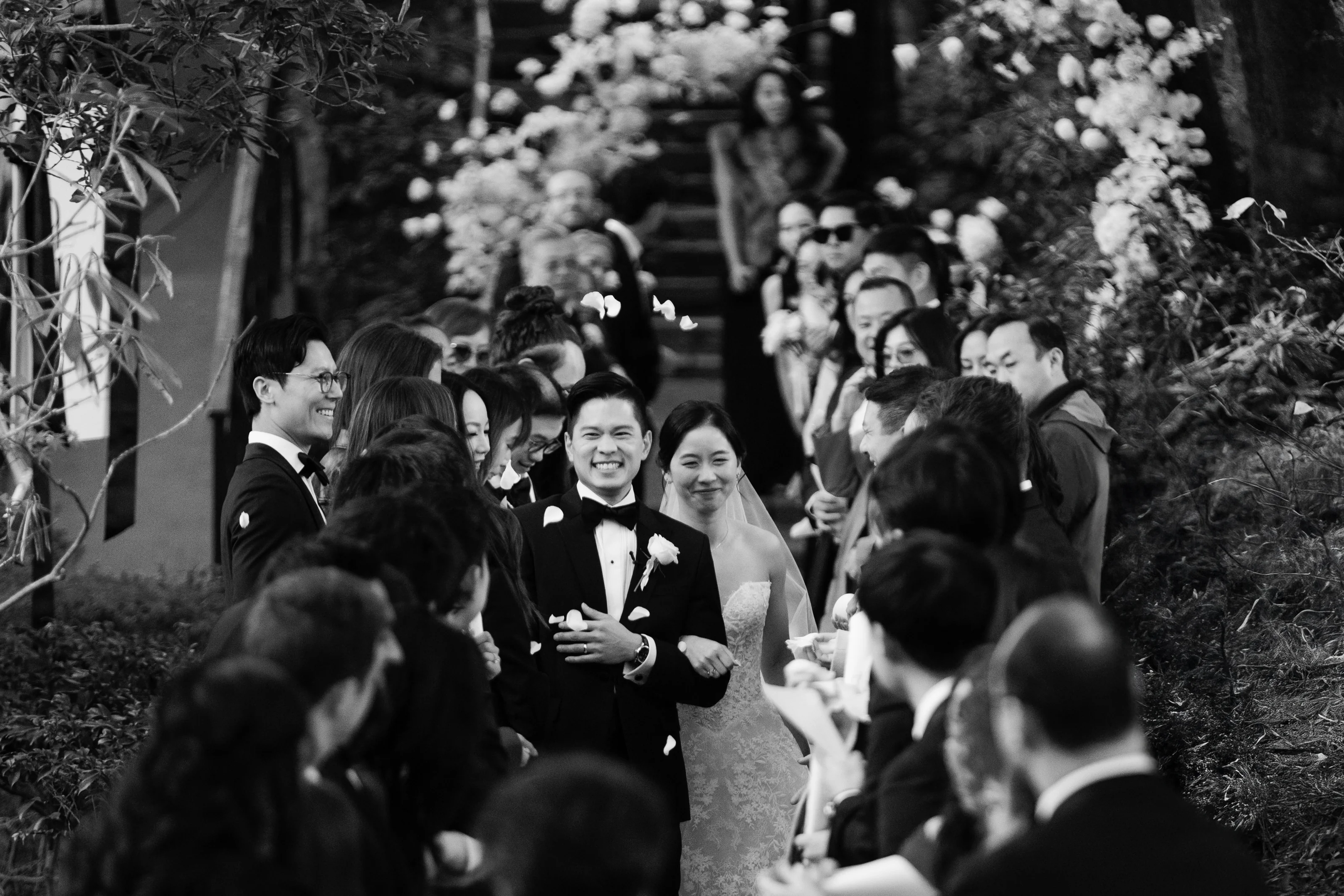 Newlyweds laugh as guests shower them with flower petals at their wedding at Jinya.